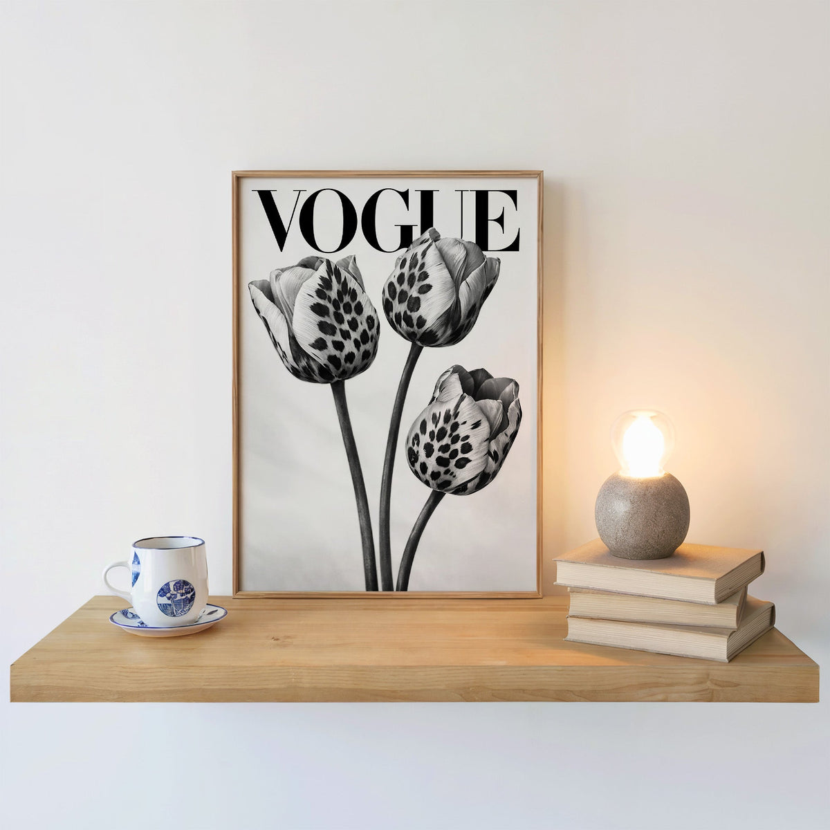 Three tulips with leopard spot petals print in an oak frame on a floating shelf beside a glowing lamp
