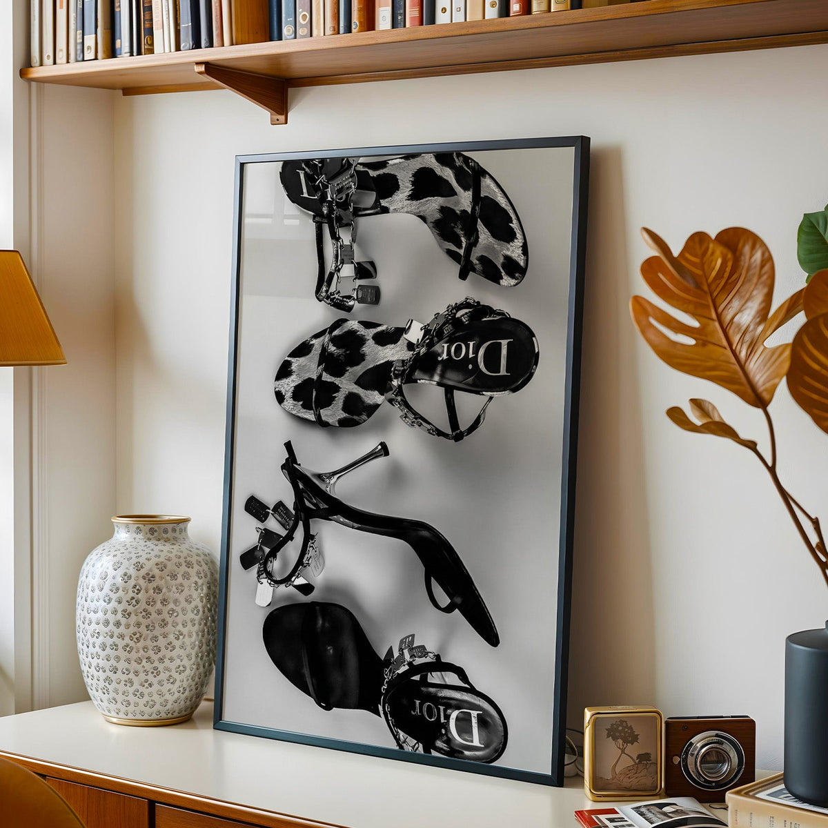 Strappy sandals with chain straps flat lay fashion print in a black frame on a console under a bookshelf