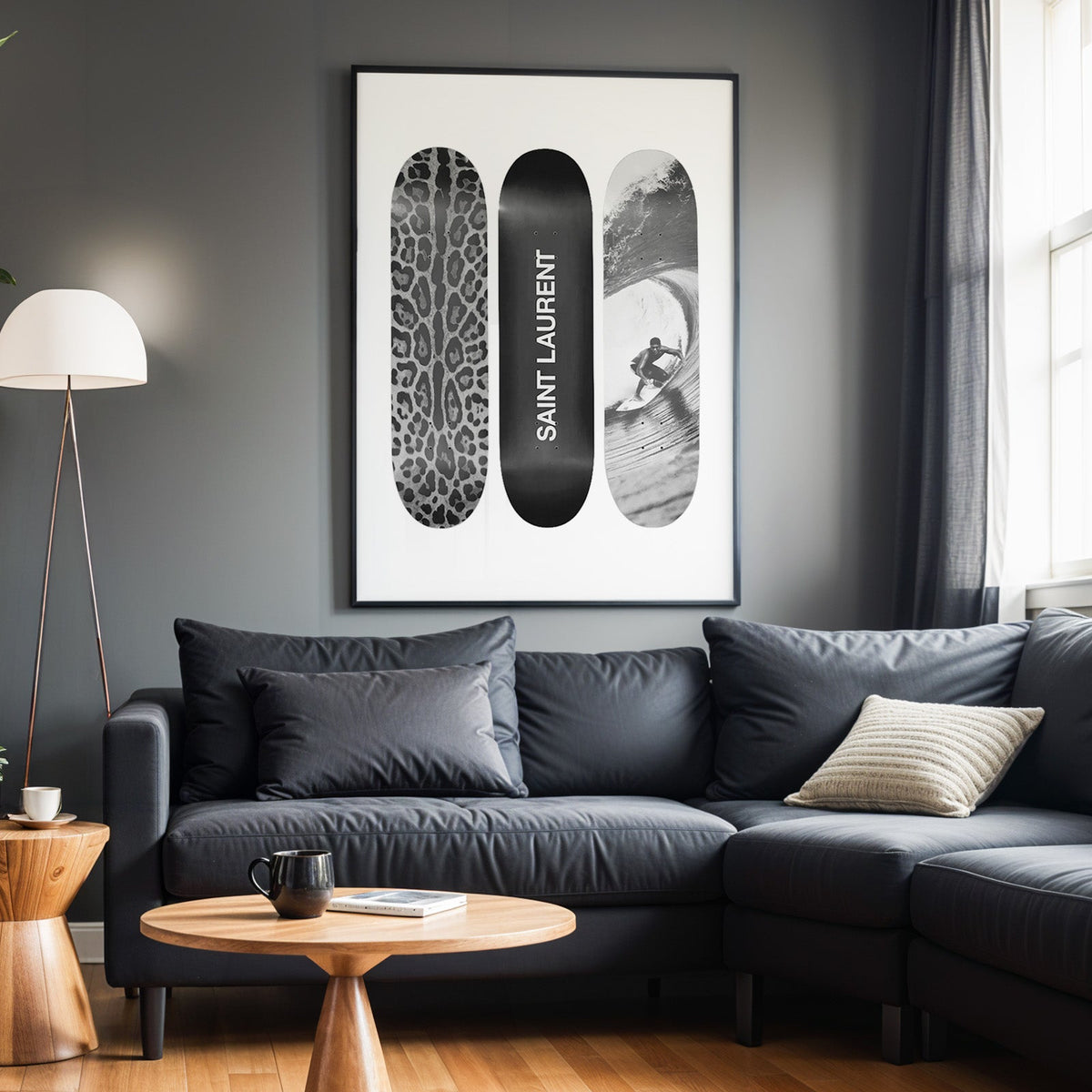 Three skateboards with leopard spots, black deck and surfer in a black frame above a charcoal sofa on a grey wall