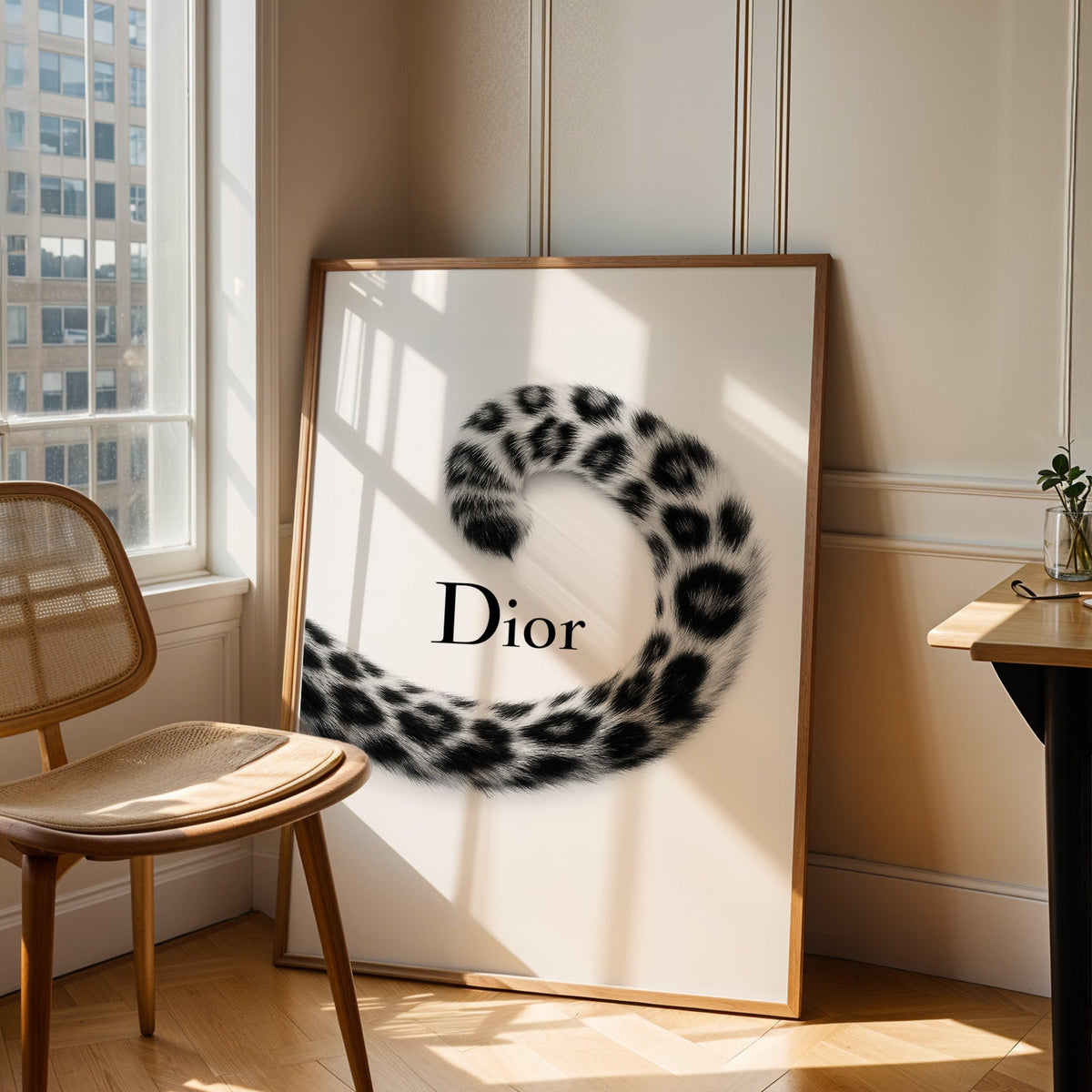 Spotted leopard tail curling around script wordmark print in an oak frame leaning in a sunlit corner beside a cane chair