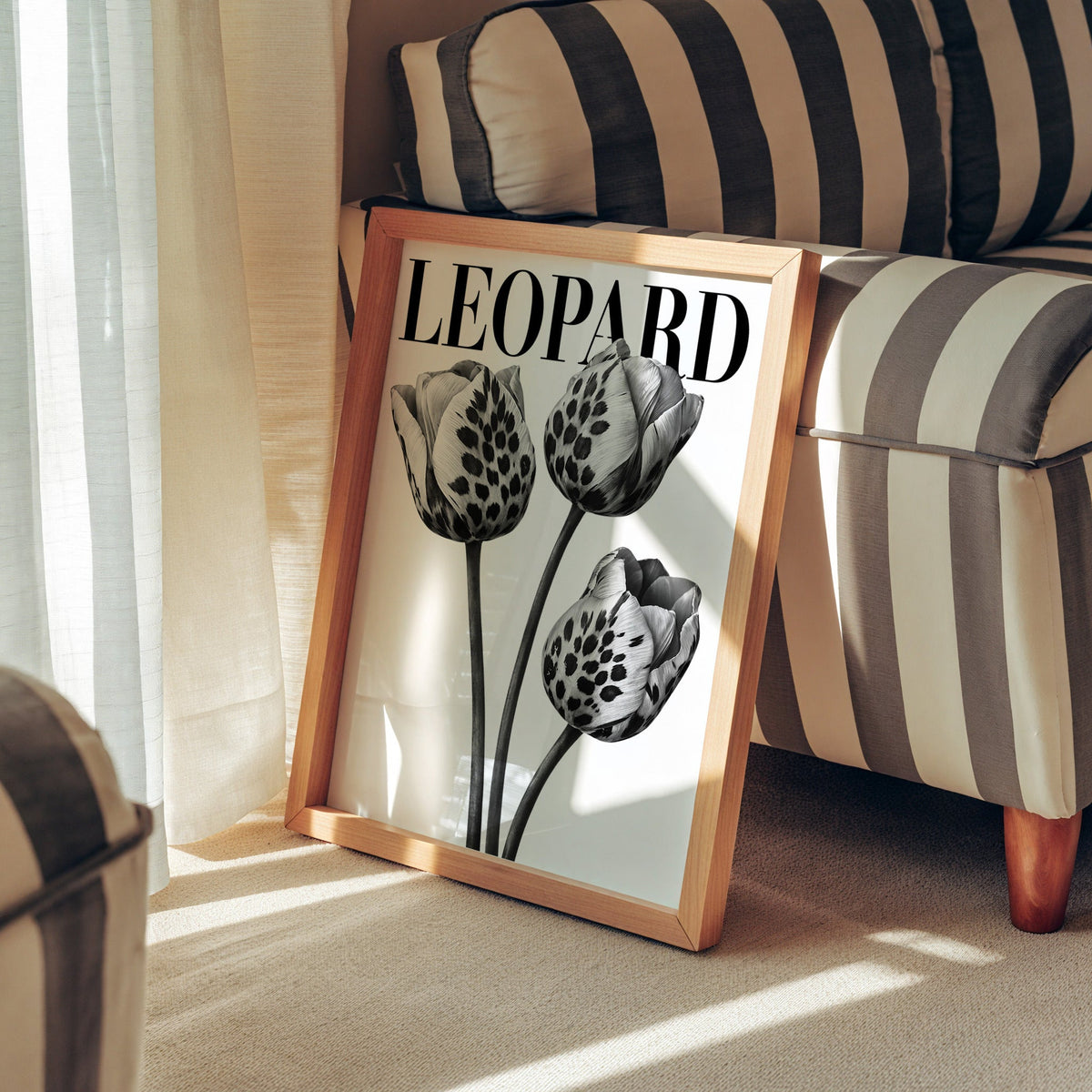 Three leopard-spotted tulips with LEOPARD title print in a pine frame leaning against a striped armchair
