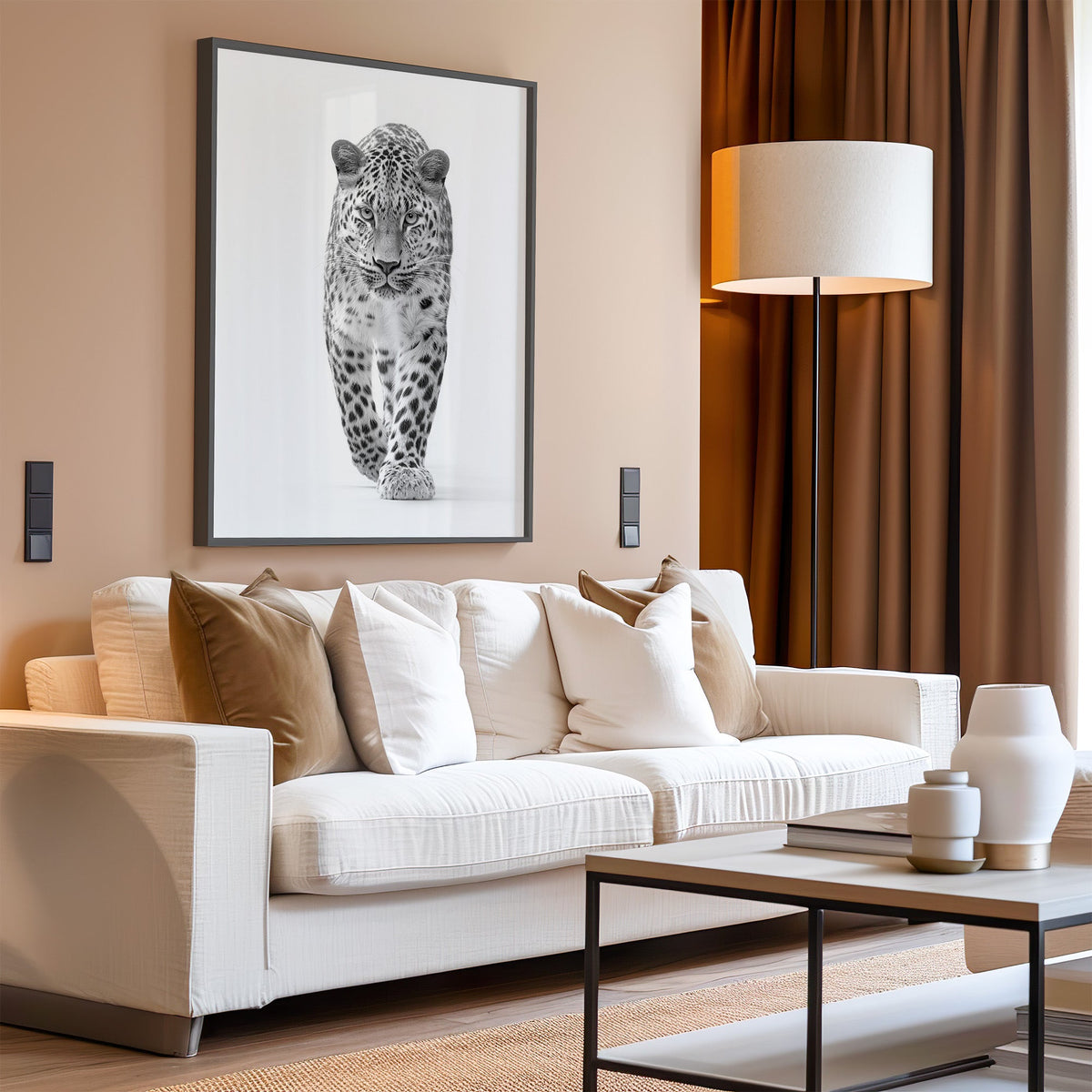 Leopard walking toward viewer black and white print in a black frame above a cream sofa on a blush living room wall
