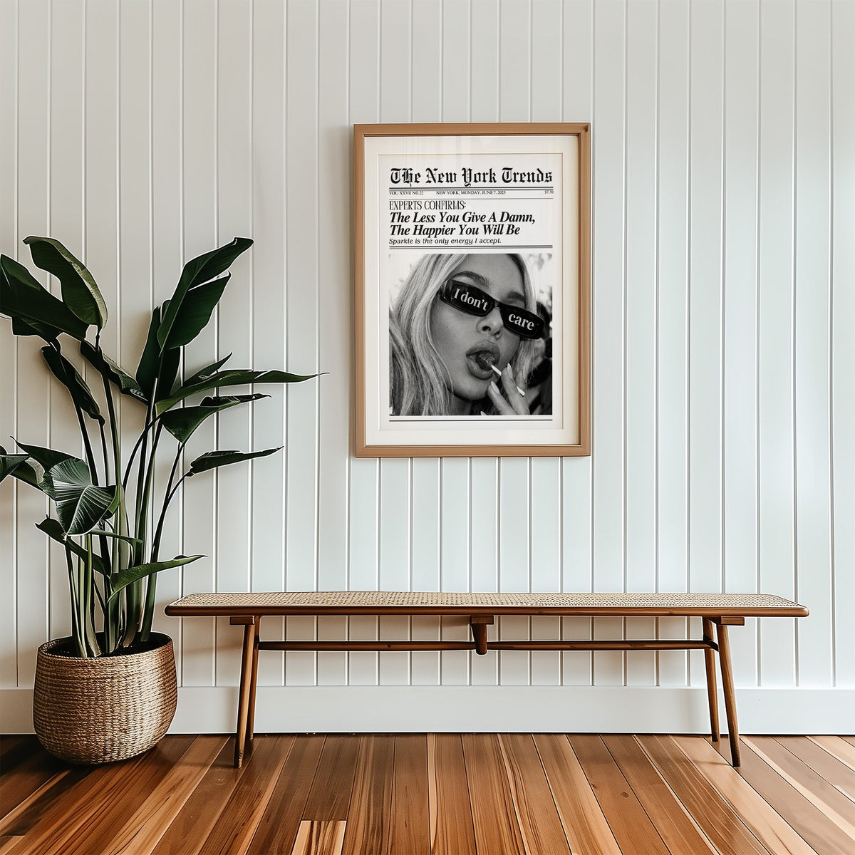 I don't care glasses and lollipop mock newspaper print in a wood frame with a white mat above a cane bench