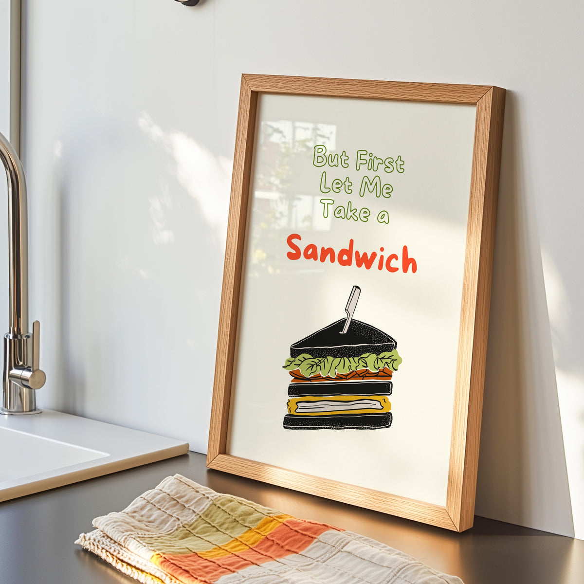 Club sandwich print in an oak frame by the kitchen sink beside a striped tea towel