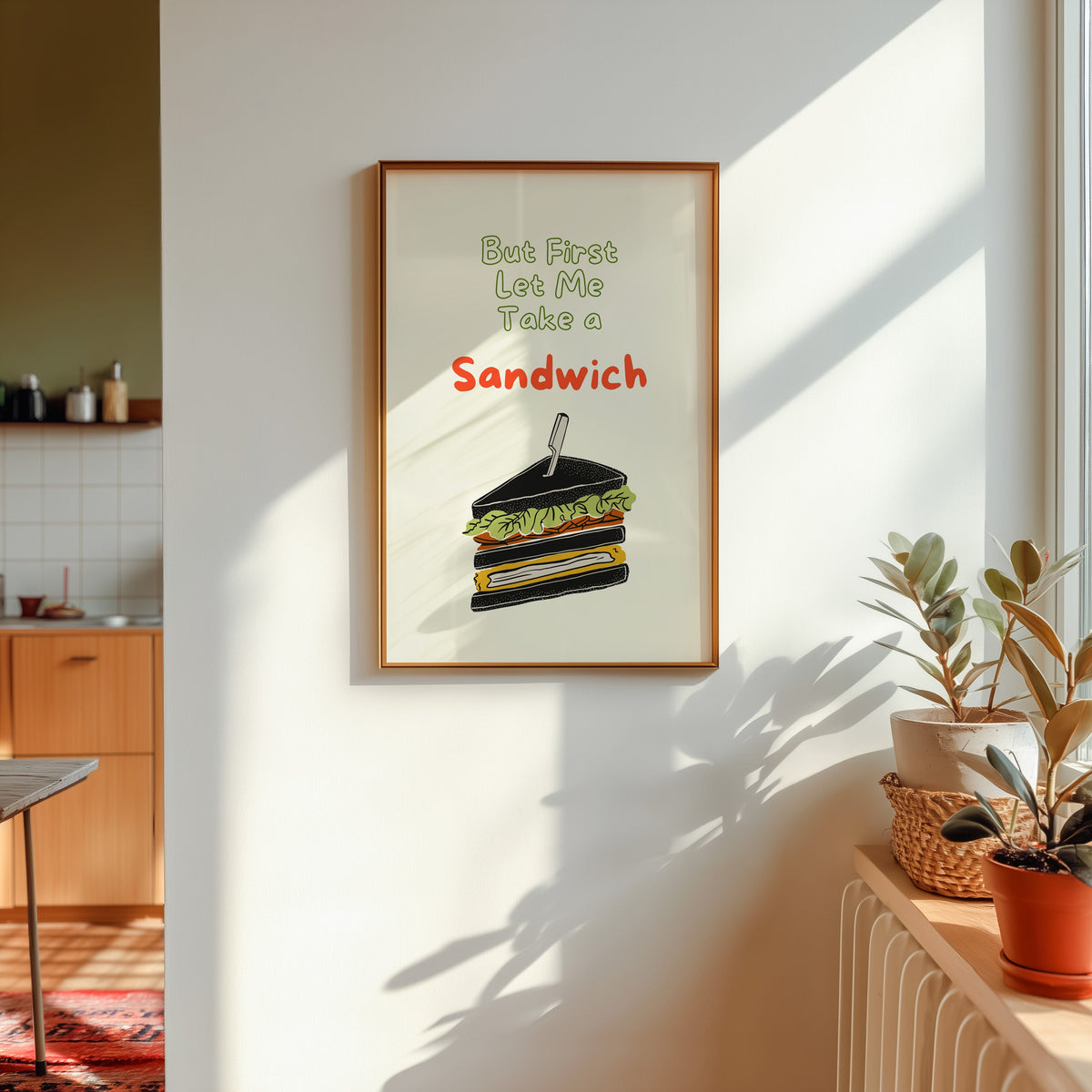 Club sandwich print shown in a gold frame in sunlight with plants and a kitchen beyond
