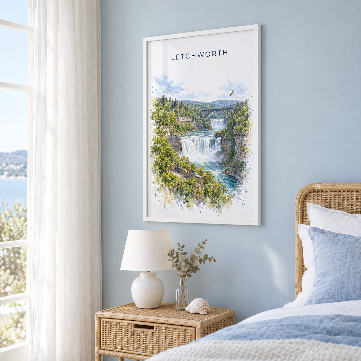 Letchworth State Park watercolor print in a white frame on a pale blue wall beside a rattan bed in a coastal bedroom