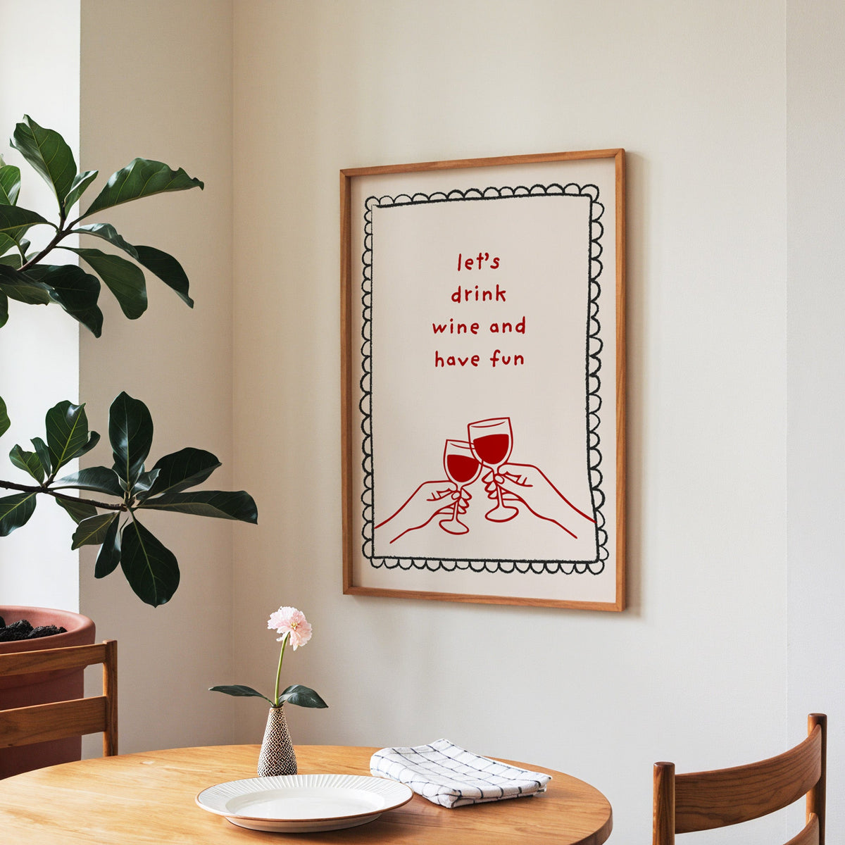 Lets Drink Wine and Have Fun print in a walnut frame above a round table beside a fiddle-leaf fig