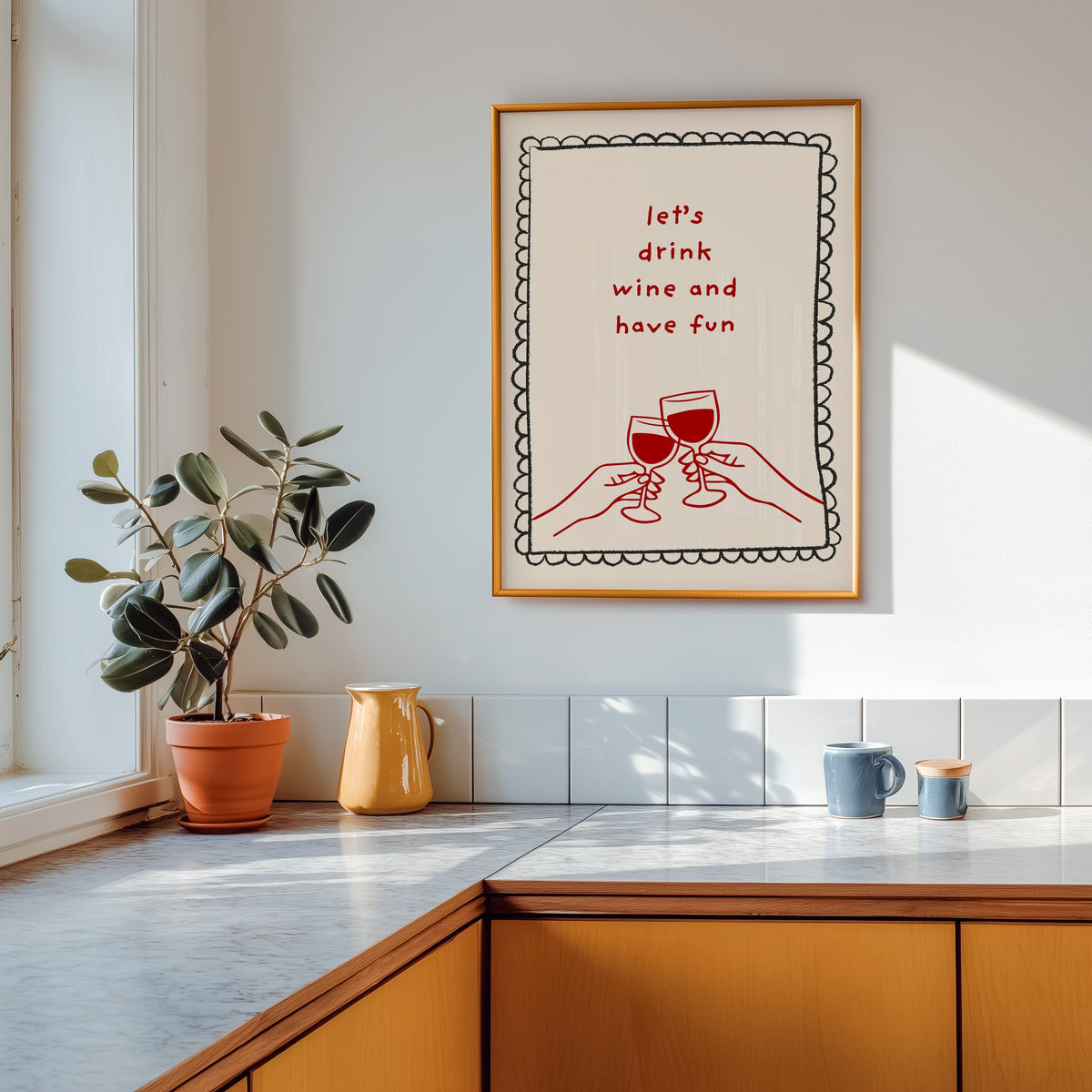 Lets Drink Wine and Have Fun print shown in a gold frame above a marble counter in a tan kitchen