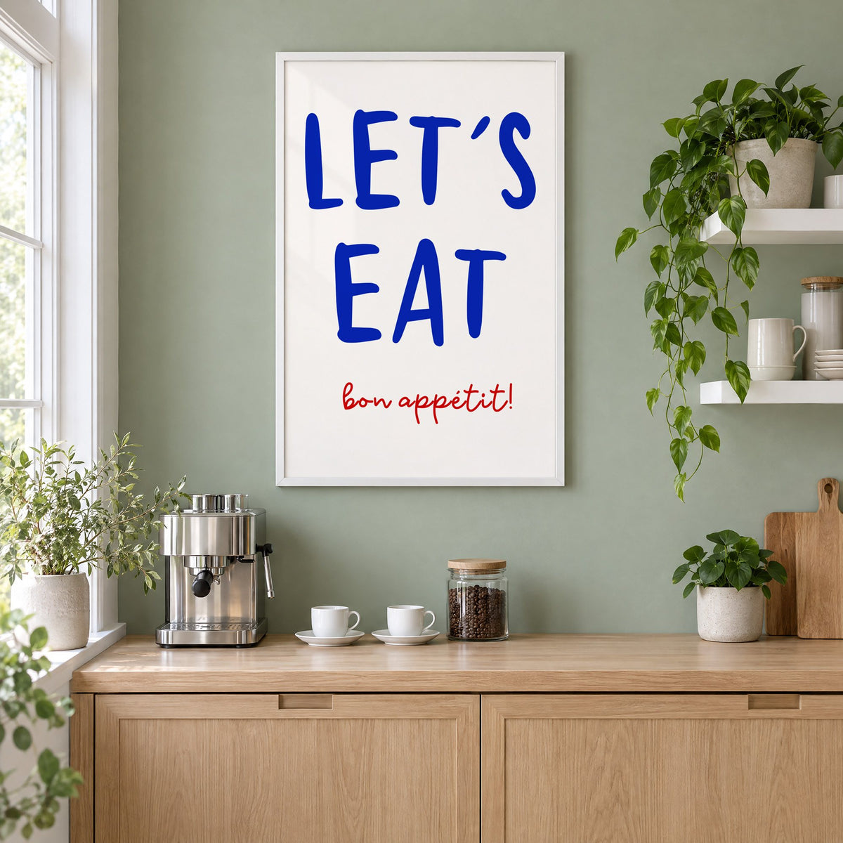 Let's Eat cobalt blue type print in a white frame on a sage green coffee nook wall above an espresso machine