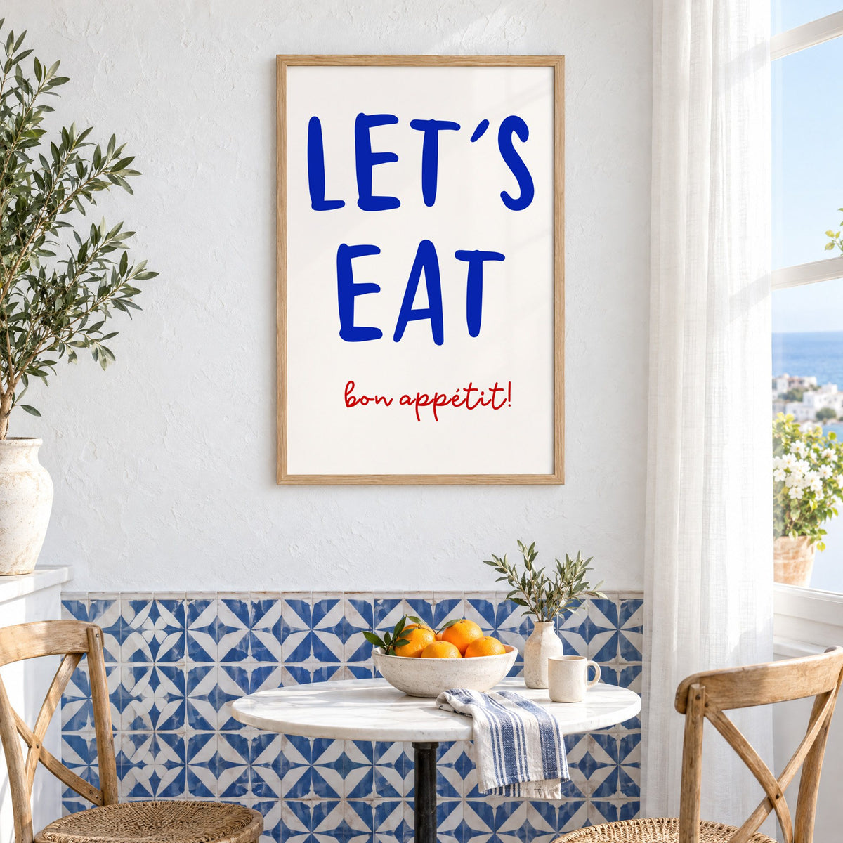 Let's Eat cobalt blue type print in an oak frame above a bistro table and blue patterned tiles