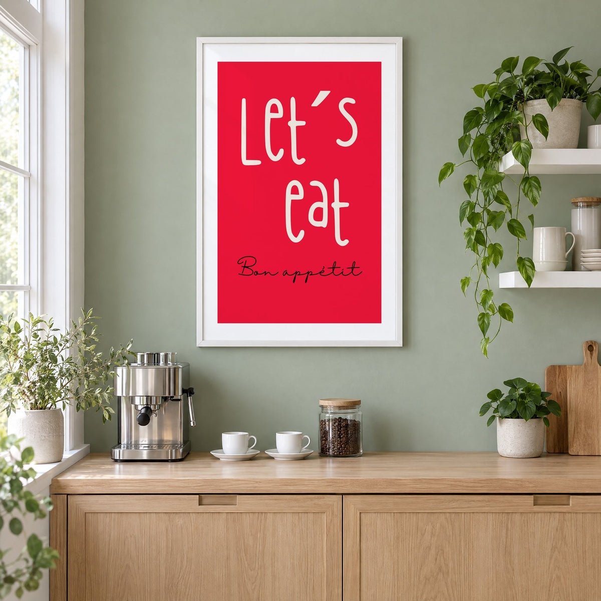 Let's eat red block print in a white frame on a sage green coffee nook wall above an espresso machine