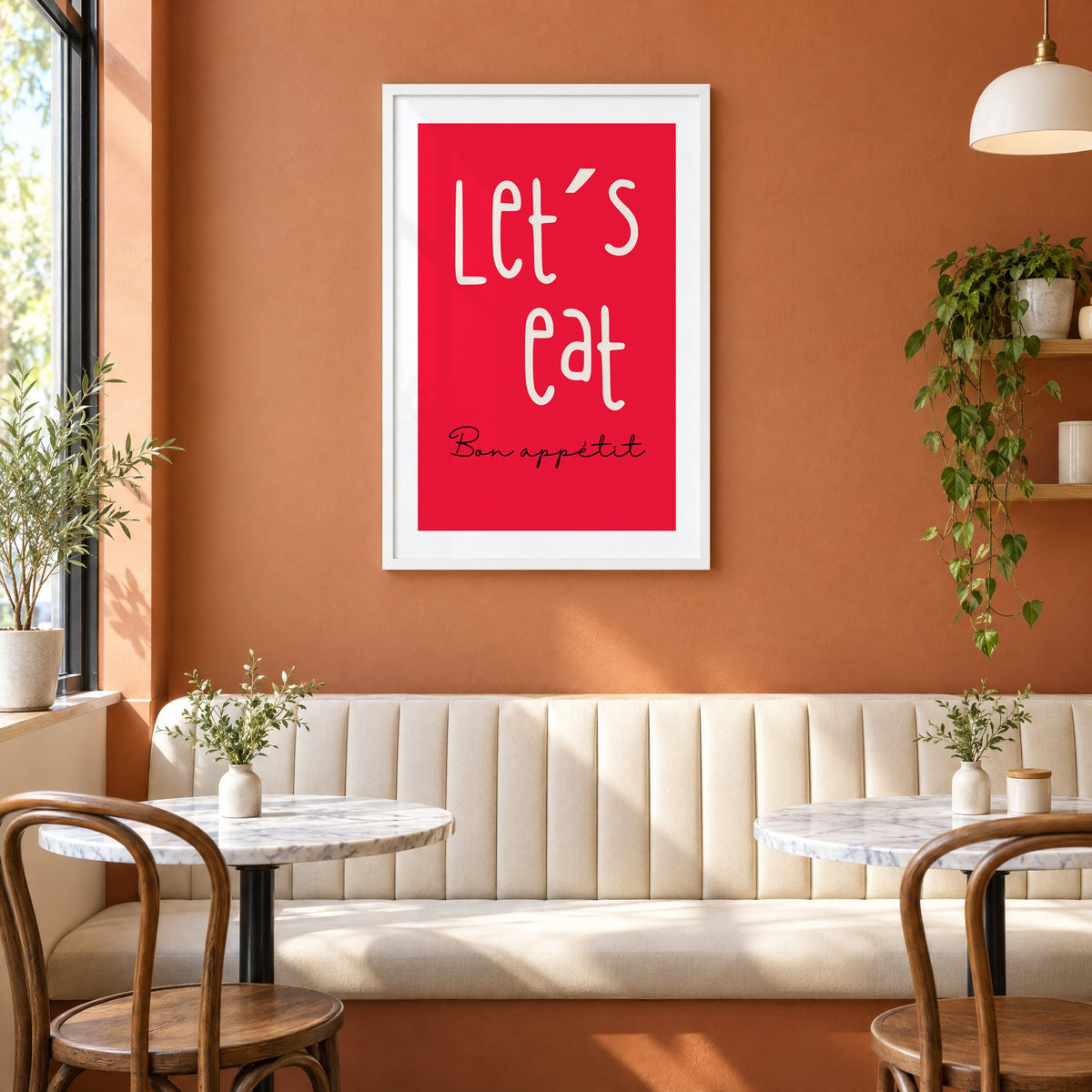 Let's eat red block print in a white frame above a cream banquette on a terracotta cafe wall