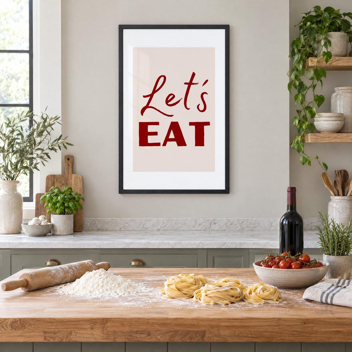Let's EAT burgundy script print in a black frame above a butcher-block island with fresh pasta, flour and cherry tomatoes