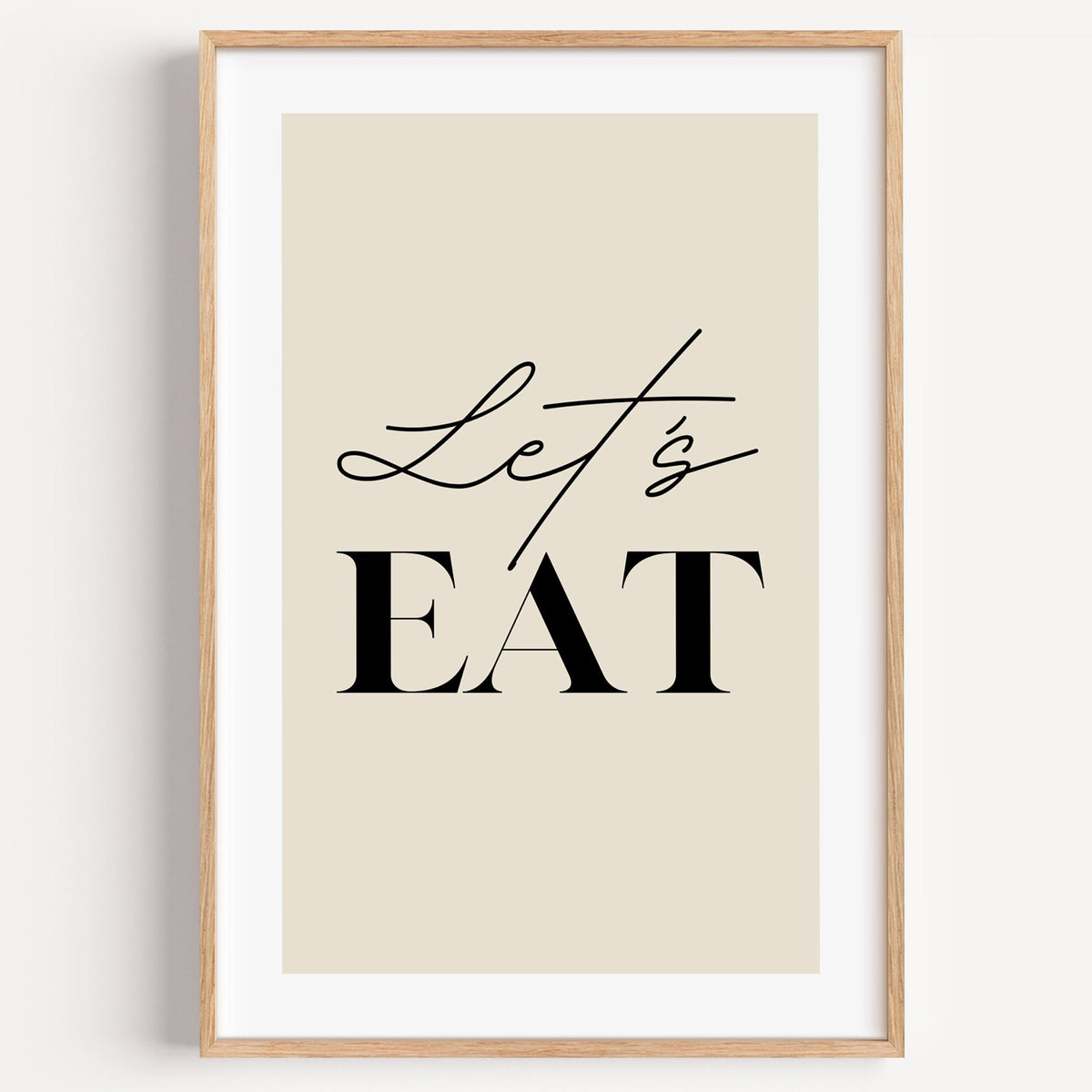 Let's EAT serif and script print in a light oak frame on a plain white wall