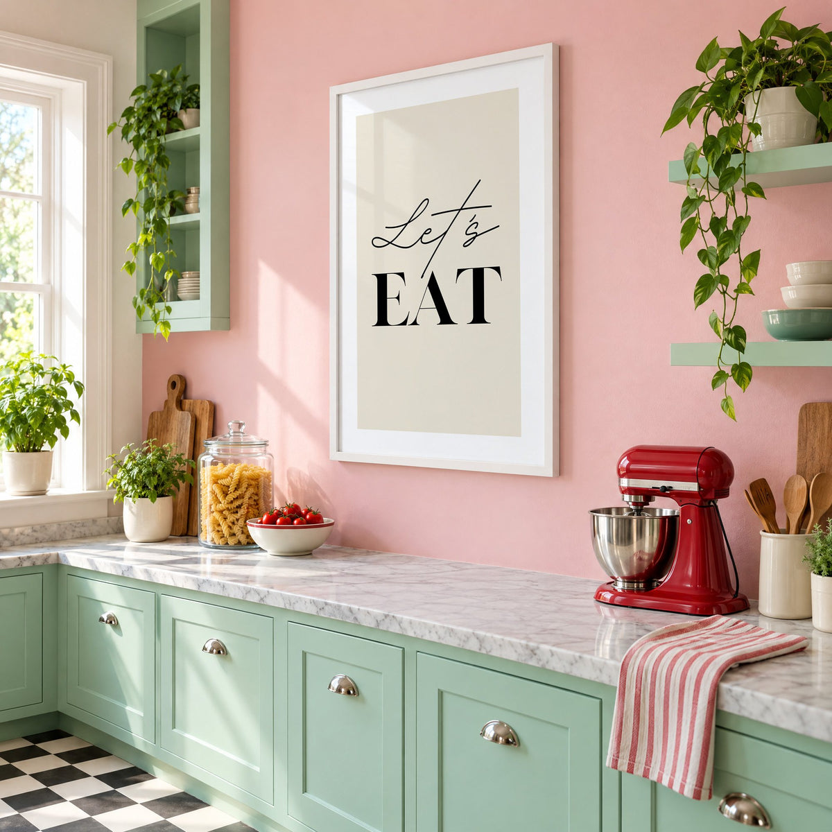 Let's EAT serif and script print in a white frame on a pink wall above mint green cabinets in a retro kitchen, seen at an angle