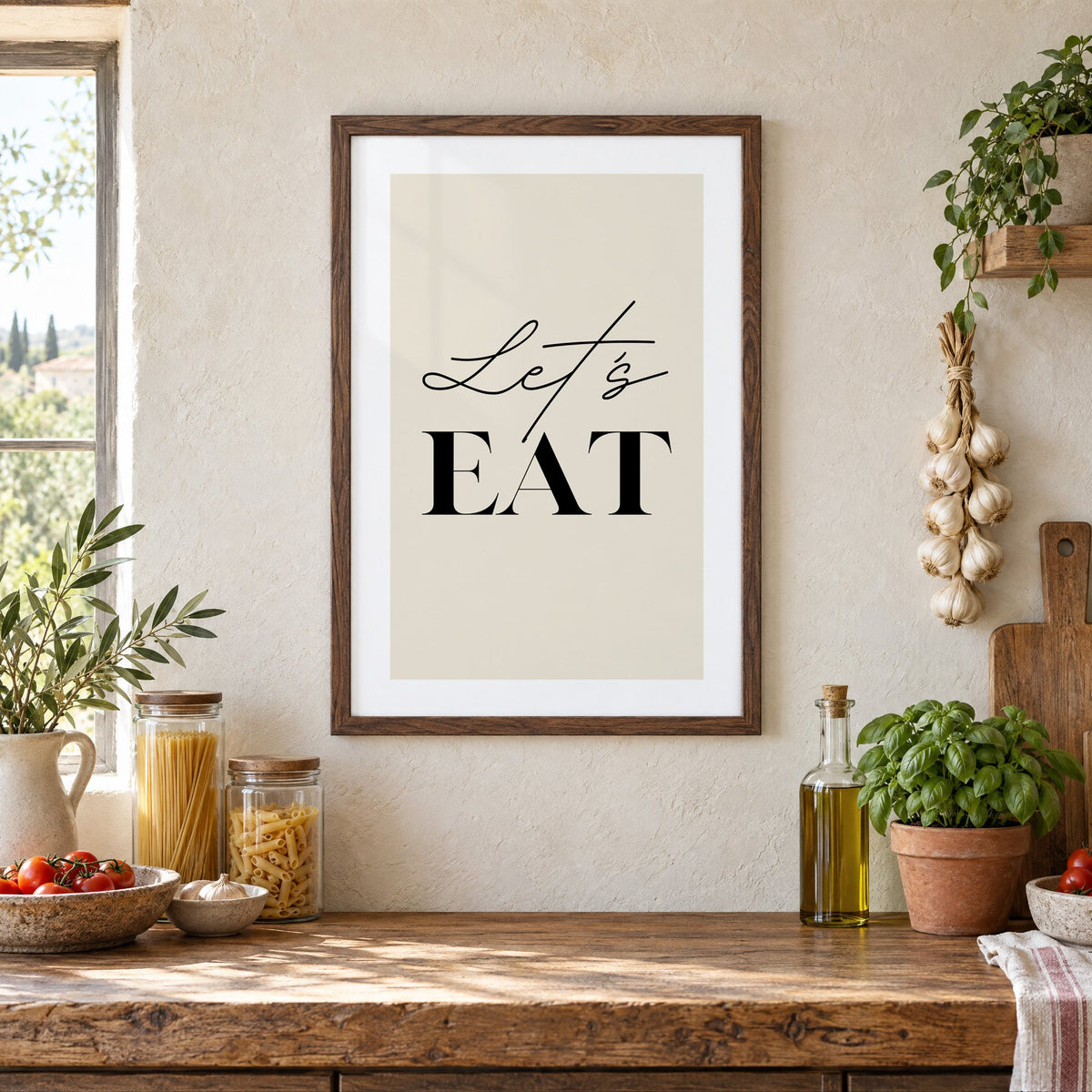Let's EAT serif and script print in a walnut frame above a rustic Italian pantry counter with pasta jars, garlic and tomatoes