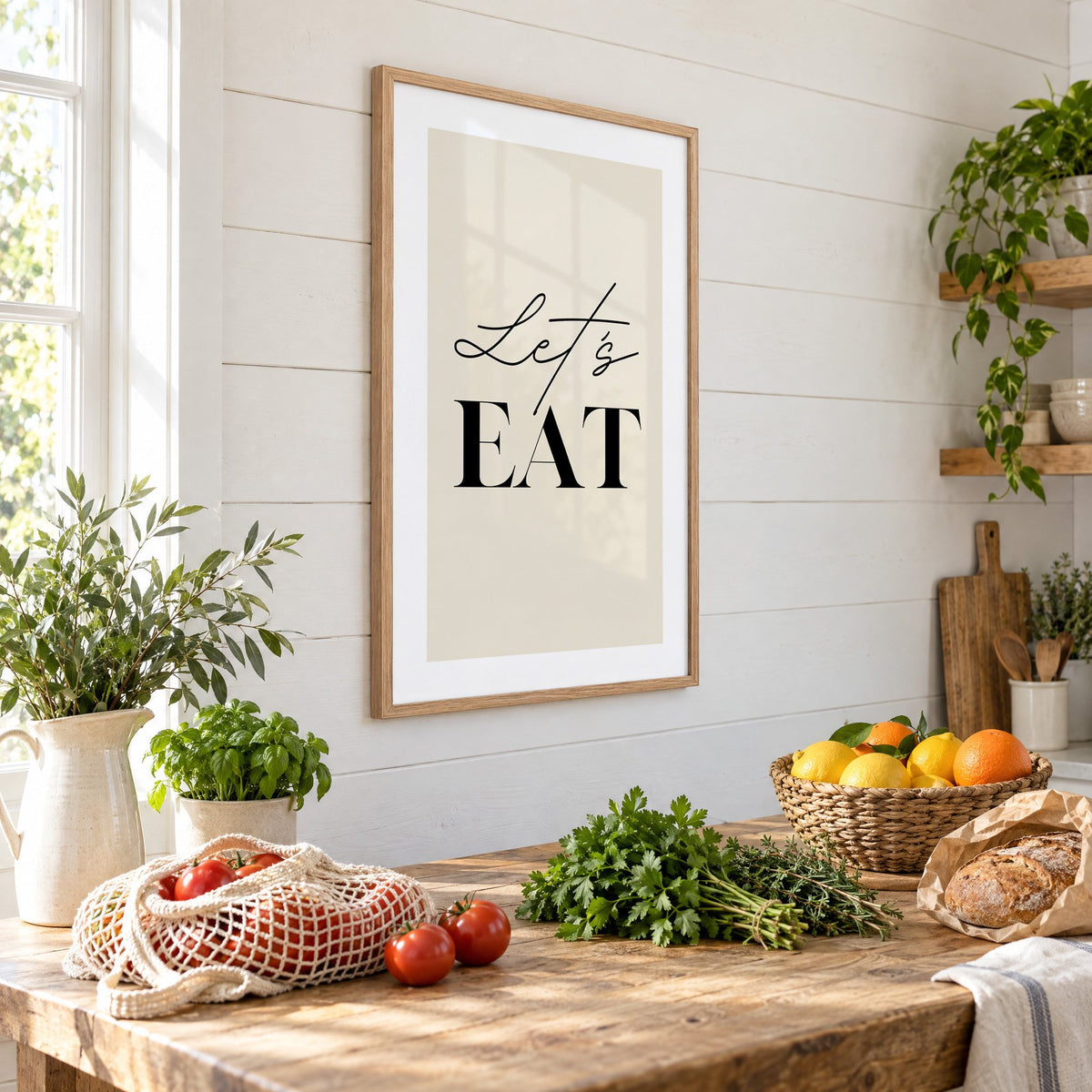 Let's EAT serif and script print in an oak frame on a shiplap wall above a farm table with market tomatoes and citrus, seen at an angle