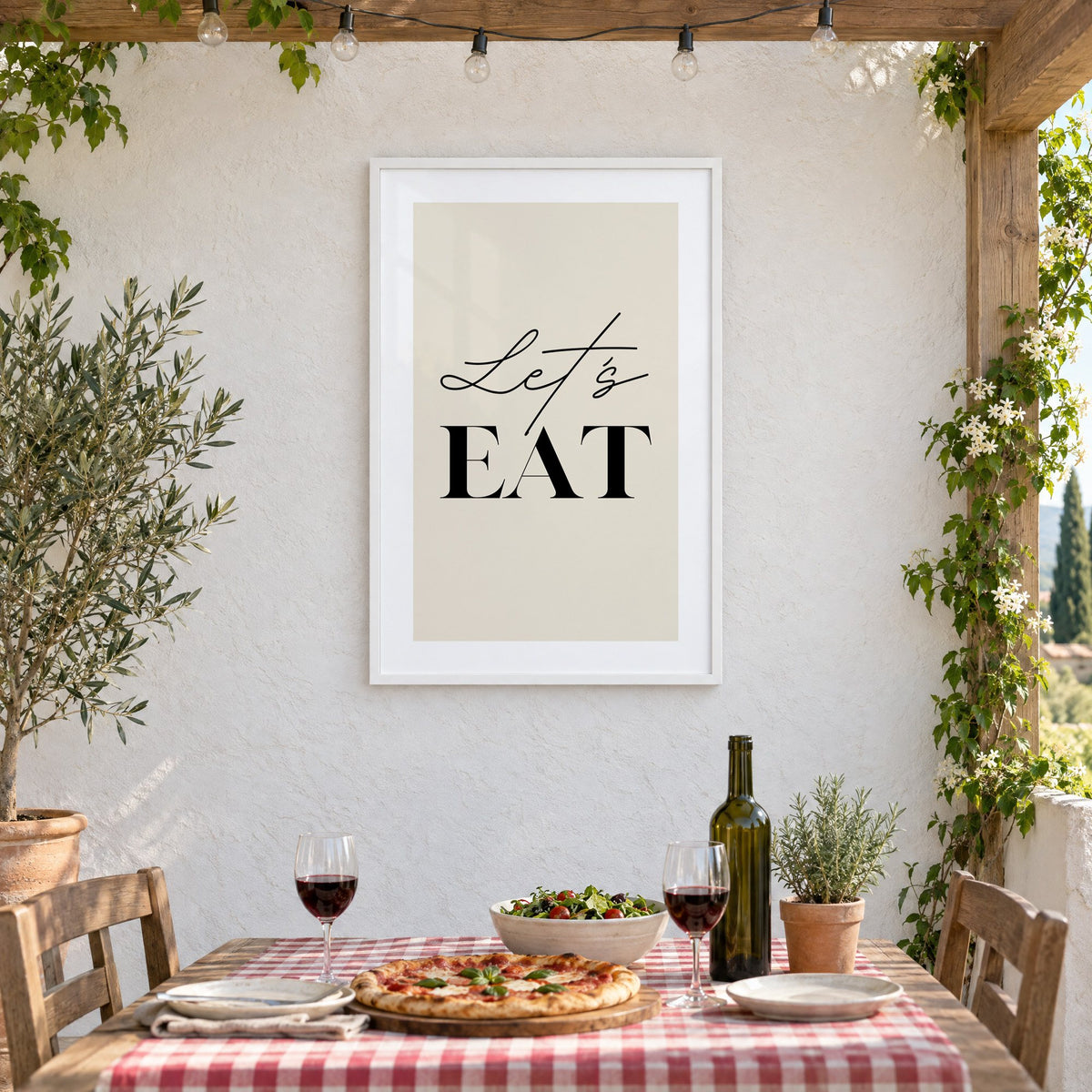 Let's EAT serif and script print in a white frame on a stucco wall above a checked-cloth table with pizza and red wine