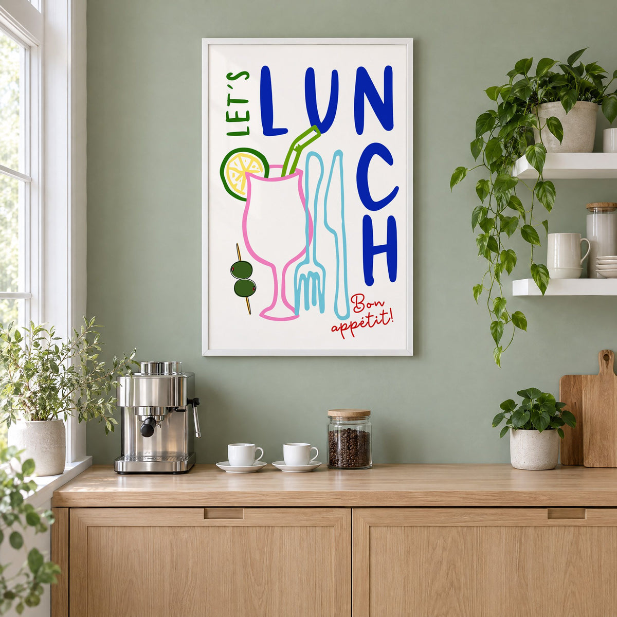 Let's Lunch cocktail and cutlery print in a white frame on a sage green coffee nook wall above an espresso machine