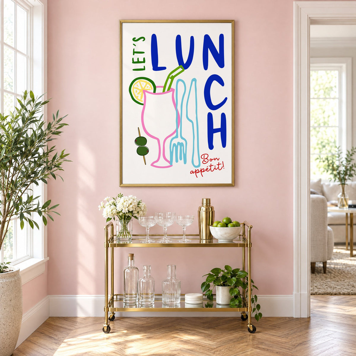 Let's Lunch cocktail and cutlery print in a brass frame above a gold bar cart on a blush pink wall