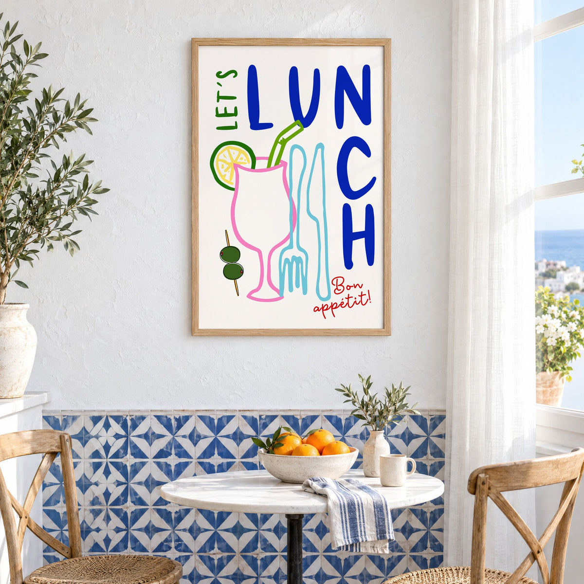 Let's Lunch cocktail and cutlery print in an oak frame above a bistro table and blue patterned tiles