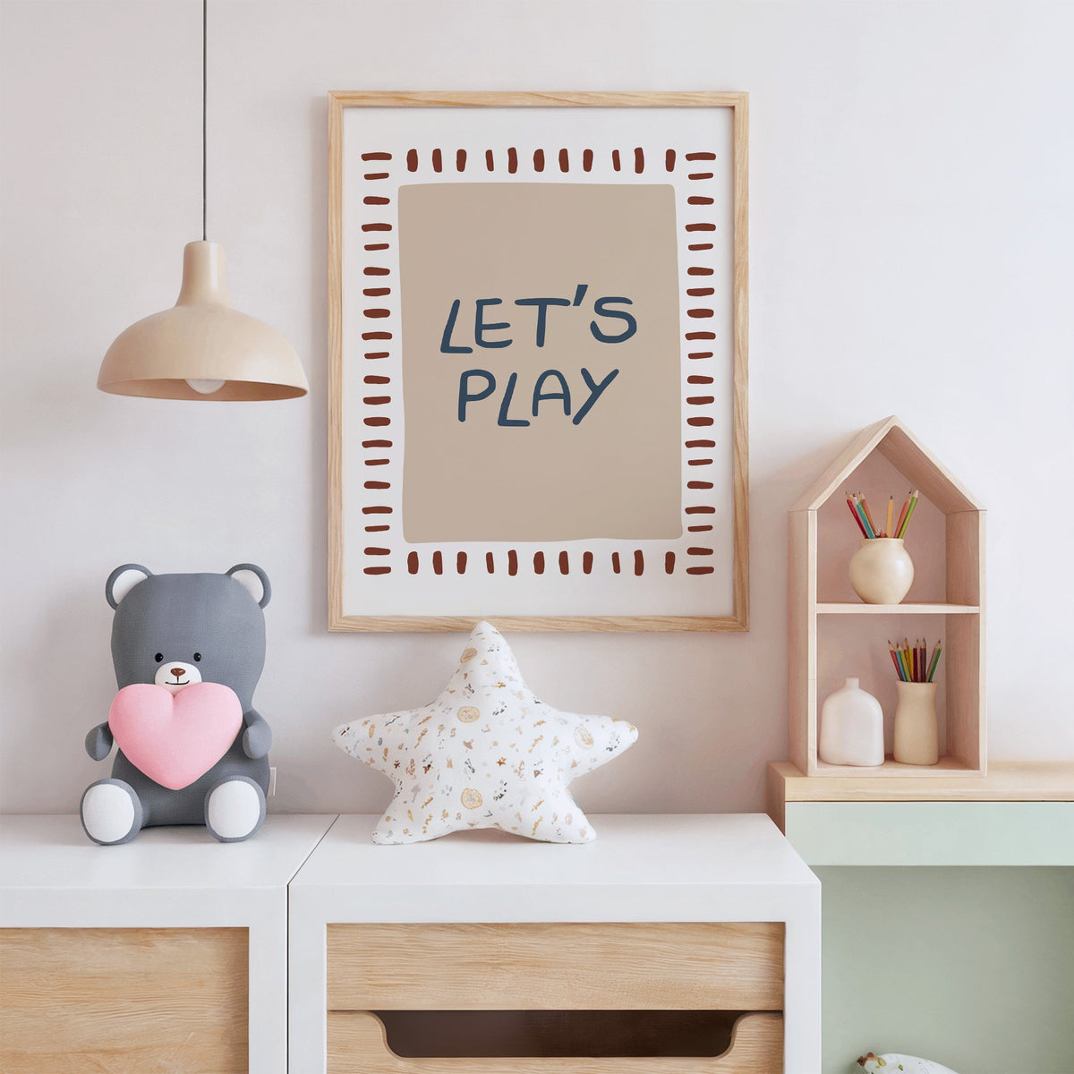 Lets play typography nursery print in an oak frame above a white dresser with a star pillow and house shelf