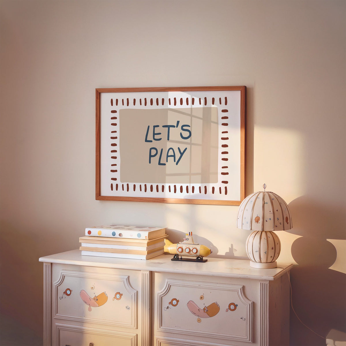 Landscape lets play typography nursery print in a cherry wood frame above a painted dresser and lamp