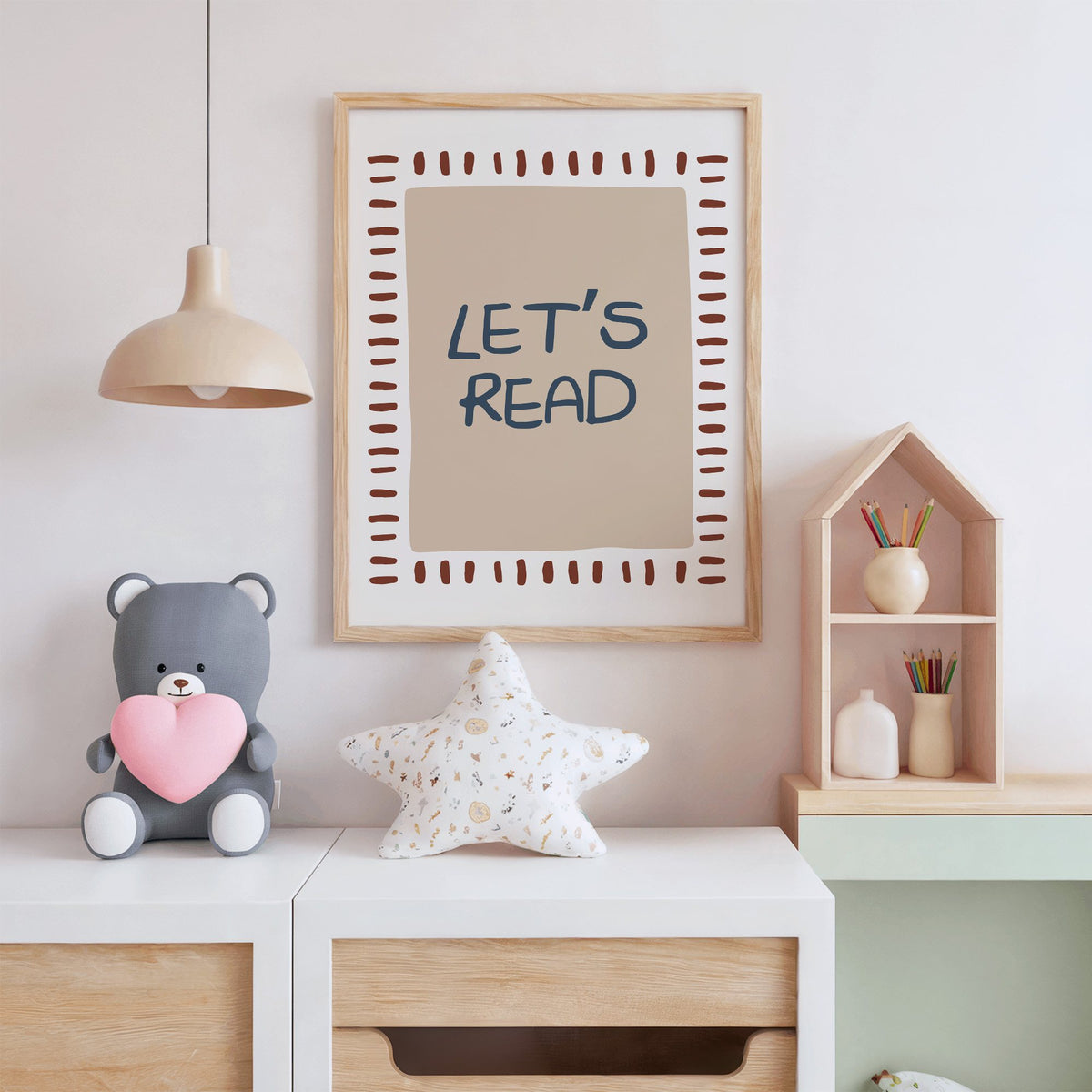 Lets read typography nursery print in an oak frame above a white dresser with a star pillow and house shelf