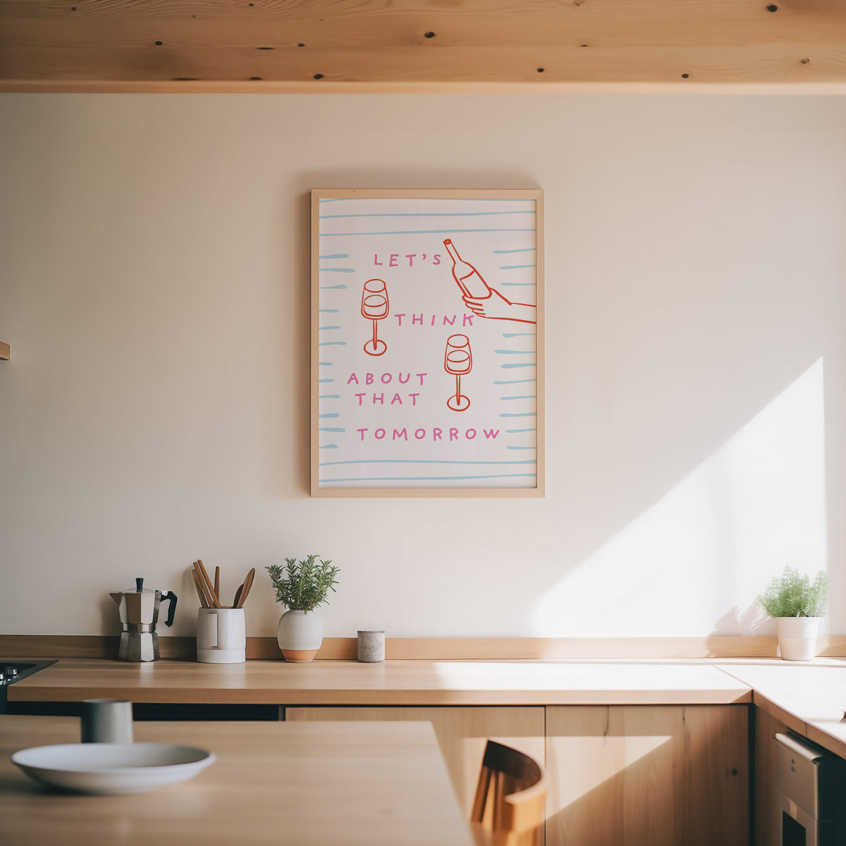 Wine pour line print in an oak frame above a wood counter with a moka pot and herbs