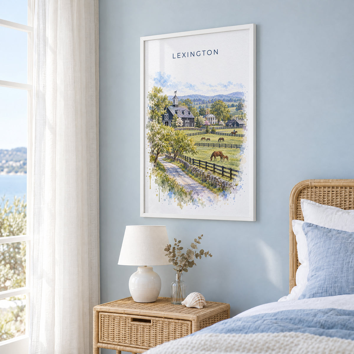 Lexington, Kentucky watercolor print in a white frame on a pale blue wall beside a rattan bed in a coastal bedroom