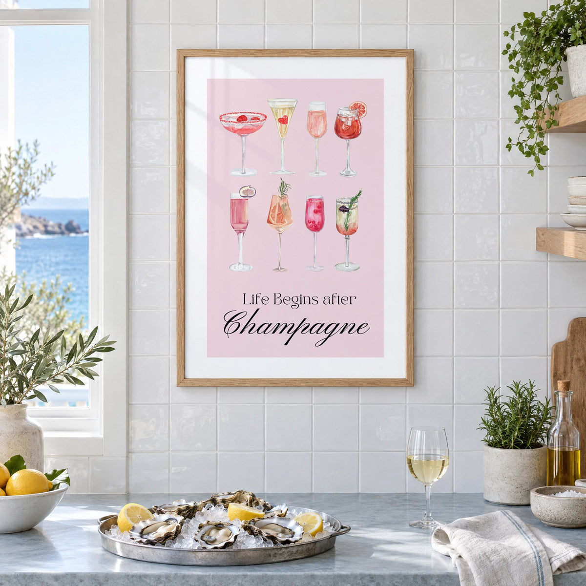 Life Begins after Champagne watercolor glasses print in an oak frame on white tiles above a marble counter with oysters and lemons by a sea view