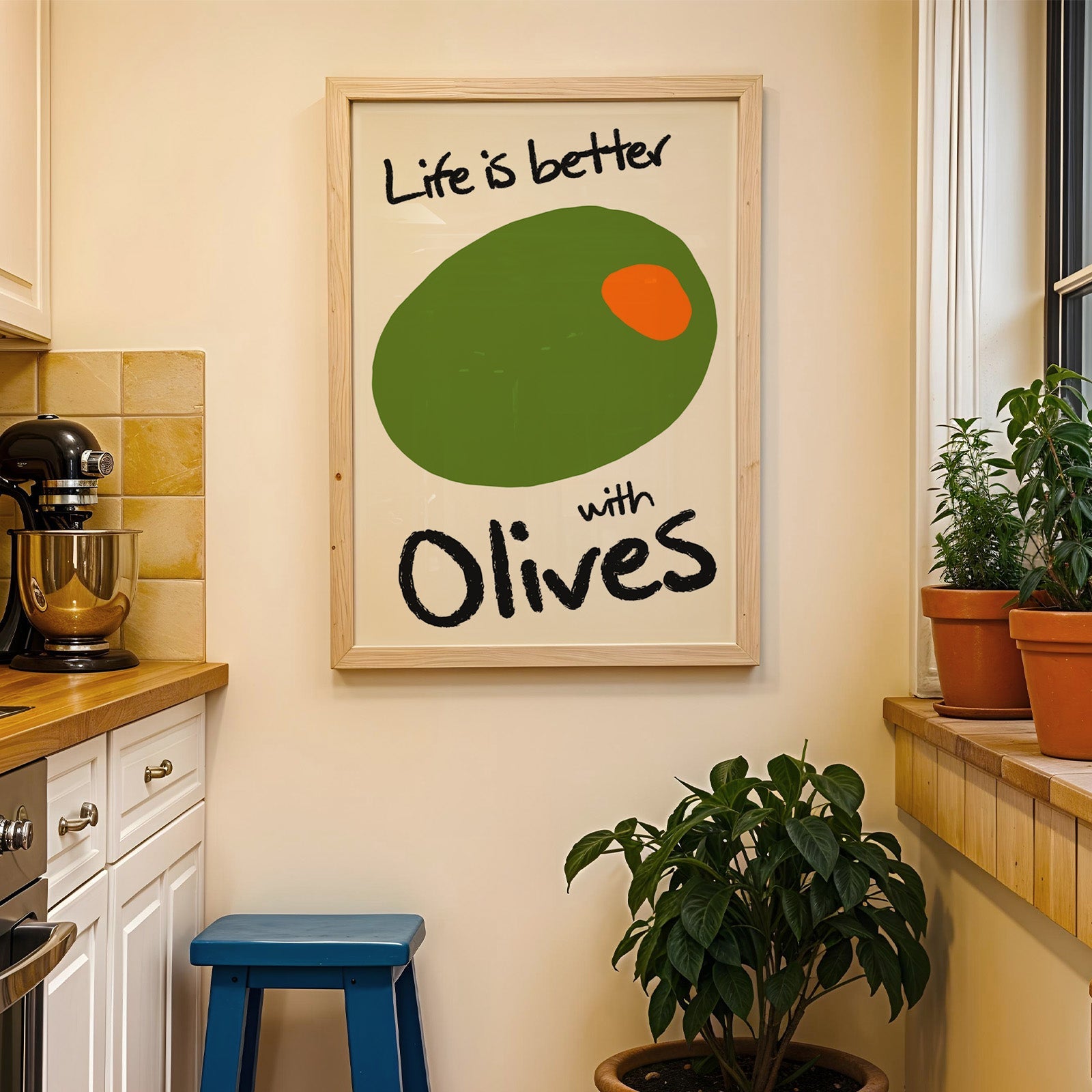 Life is better with olives print in a wood frame on a yellow tiled kitchen wall