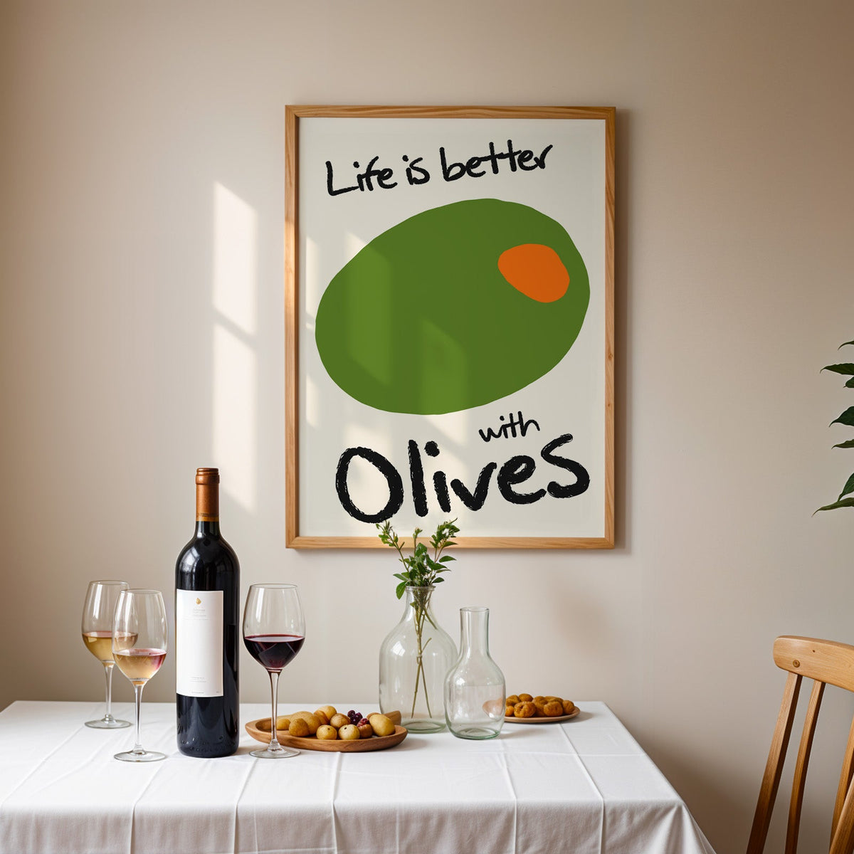 Life is better with olives print in an oak frame above a table laid with red wine