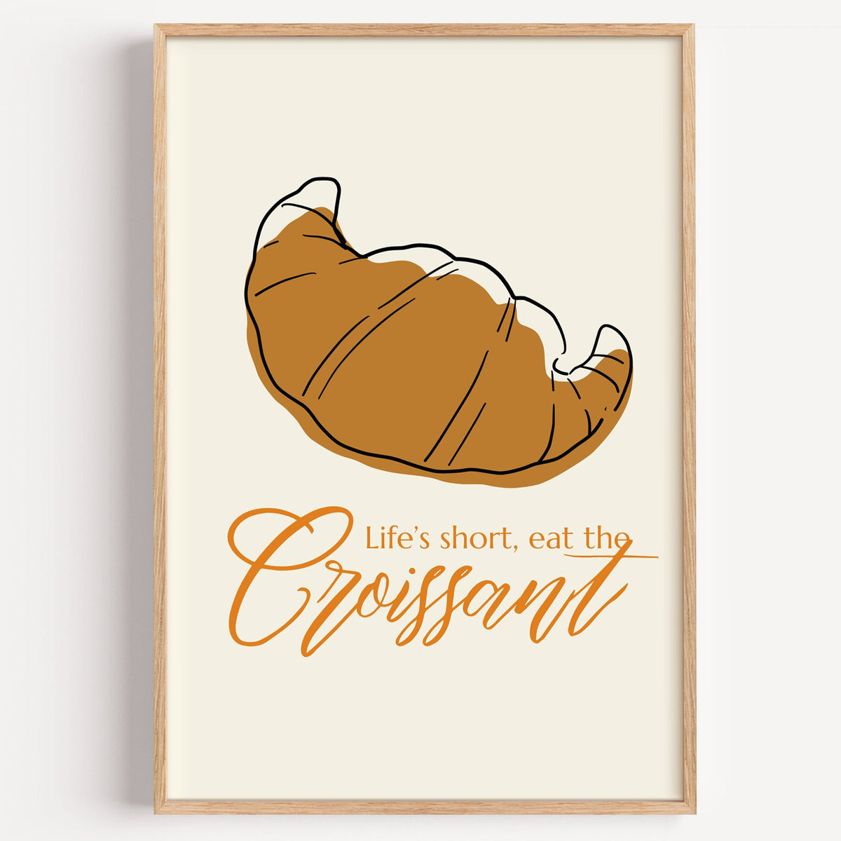 Life's short, eat the Croissant print in a light oak frame on a plain white wall