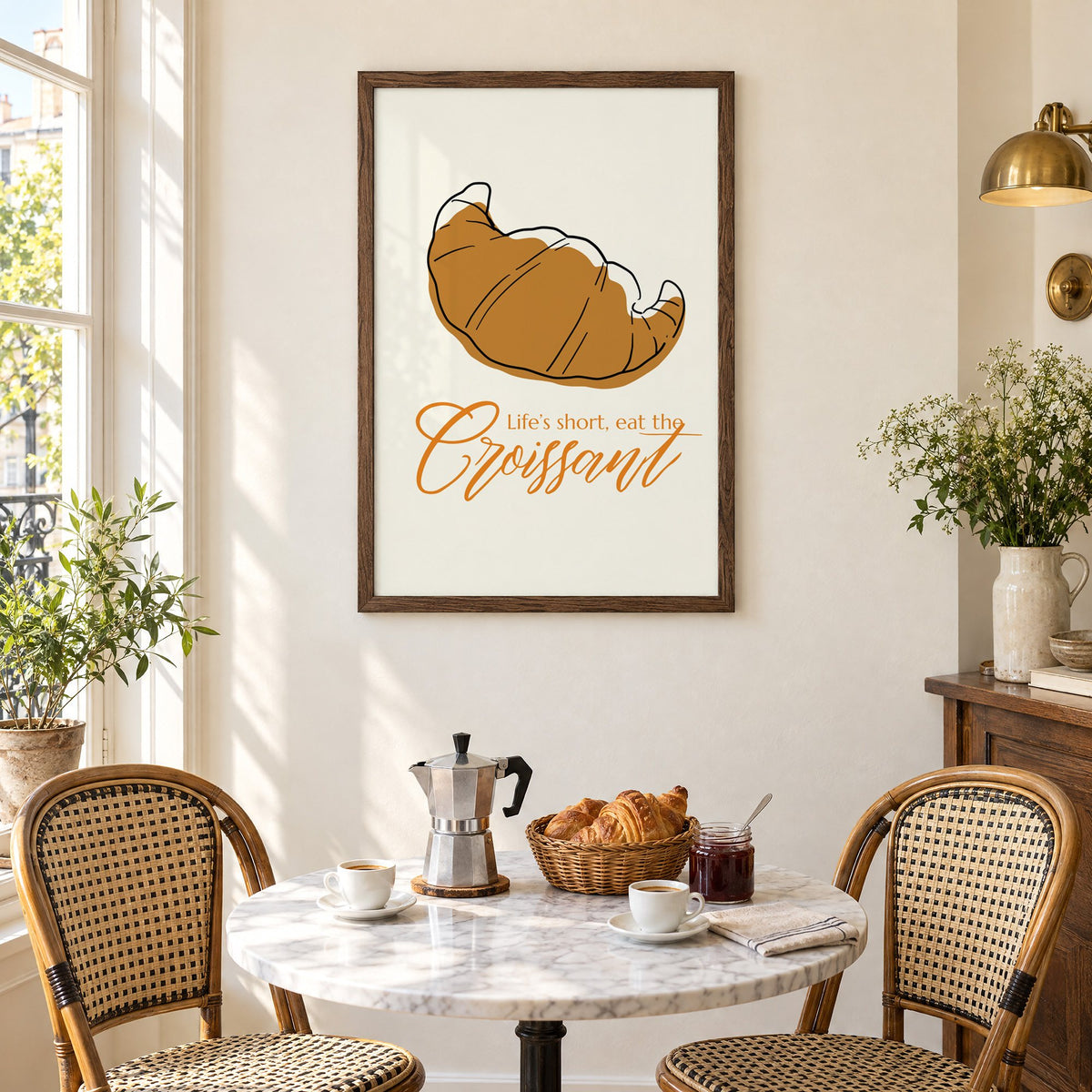 Life's short, eat the Croissant print in a walnut frame above a marble bistro table with croissants and rattan chairs