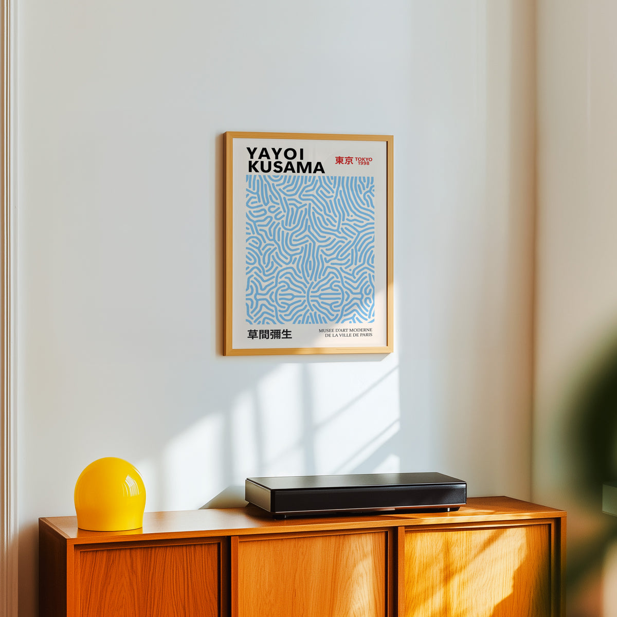 Yayoi Kusama inspired light blue squiggle pattern print above a sideboard with a yellow lamp