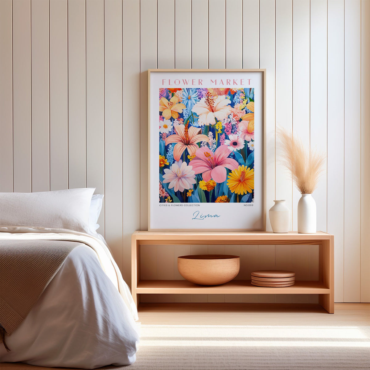 Lima flower market print in an oak frame on a wood bench against a white shiplap bedroom wall with pampas grass