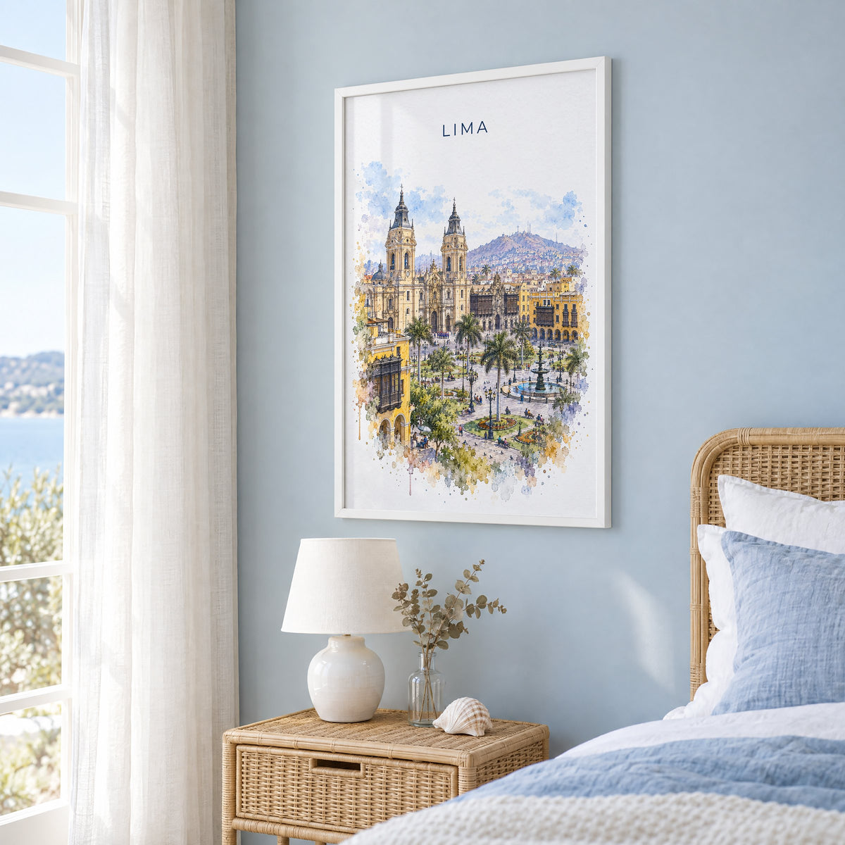 Lima, Peru watercolor print in a white frame on a pale blue wall beside a rattan bed in a coastal bedroom