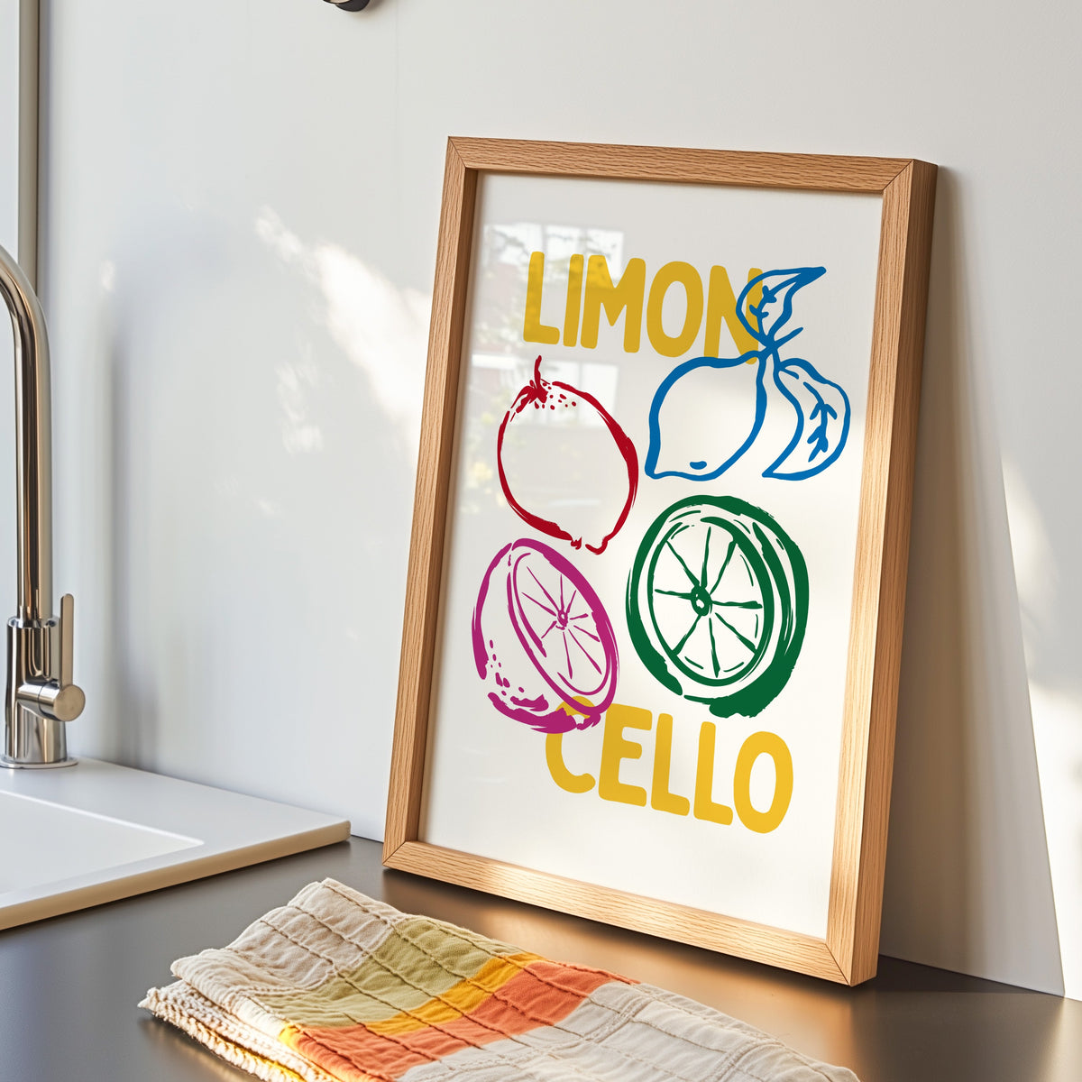Limoncello lemon sketch print in an oak frame by the kitchen sink beside a striped tea towel