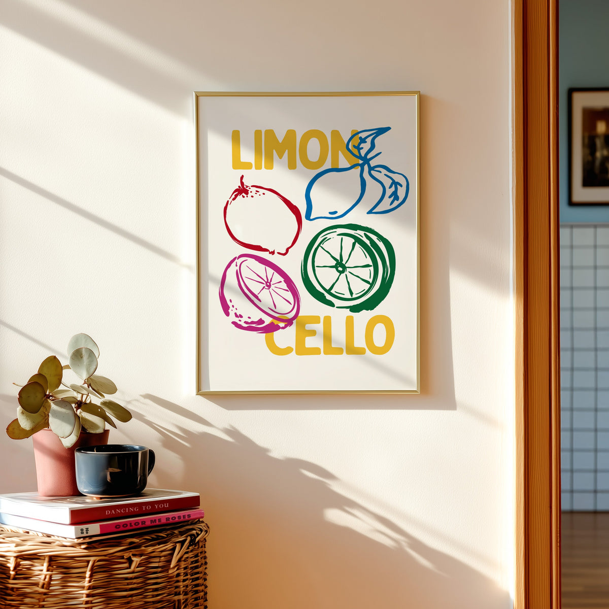 Limoncello lemon sketch print shown in a gold frame above a basket of books and a pilea plant