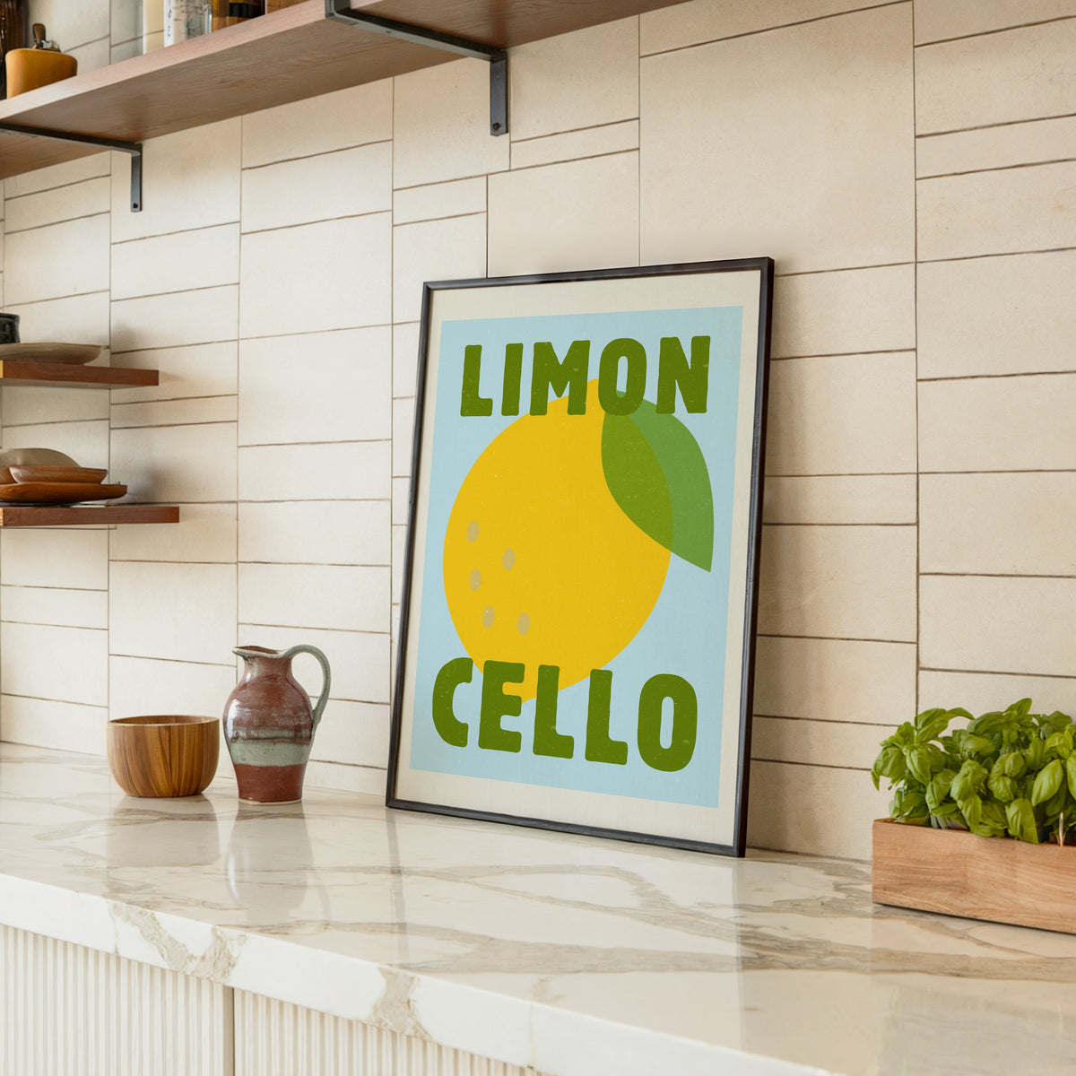 Limoncello print in a black frame leaning on a marble counter in a tiled kitchen