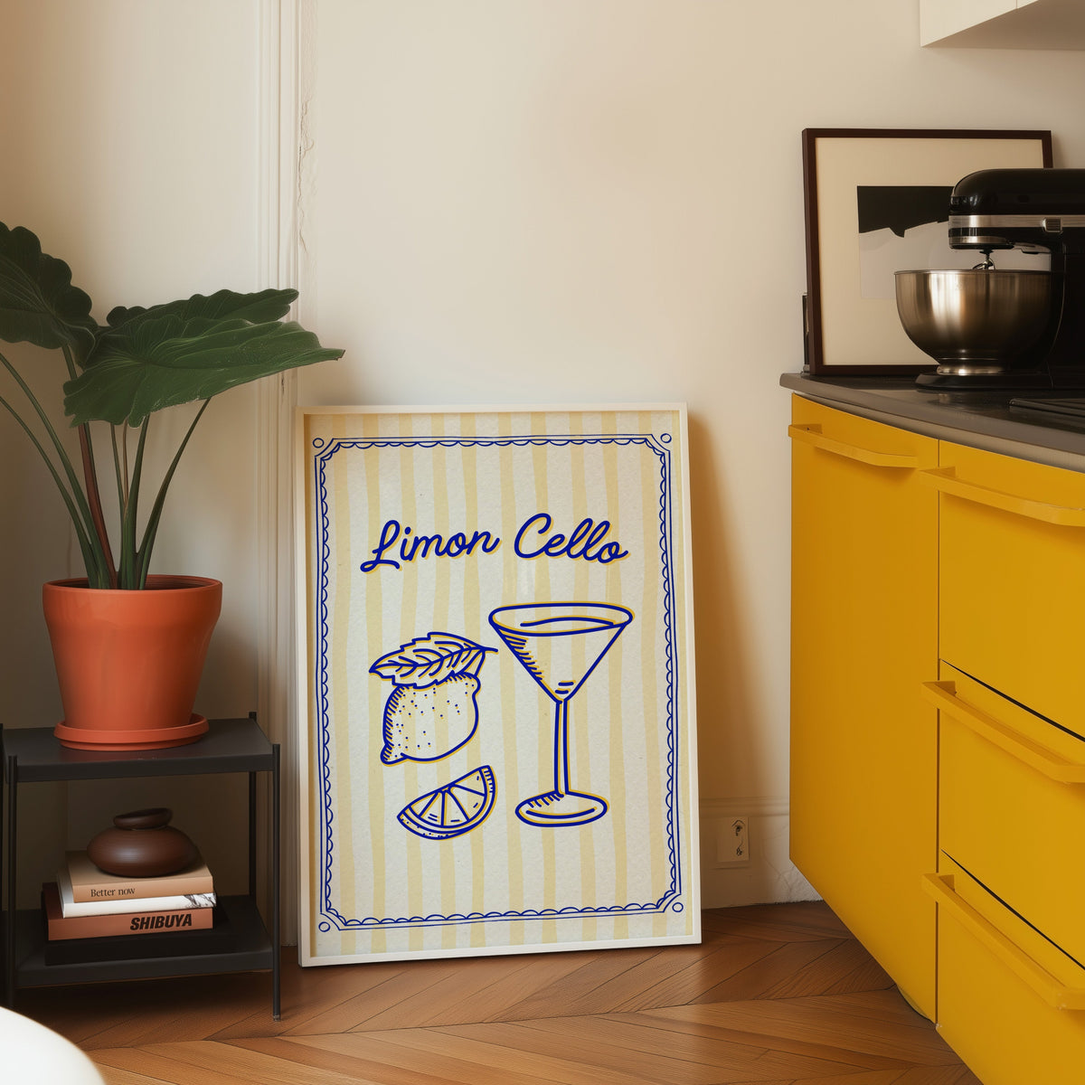 Limoncello martini print in a white frame leaning on parquet beside a bright yellow kitchen
