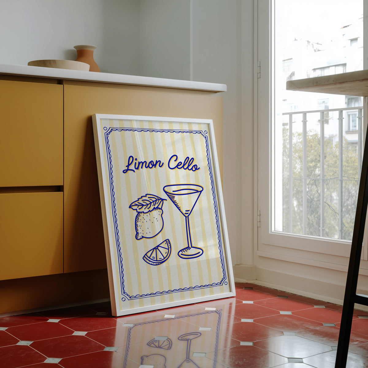 Limoncello martini print in a white frame against yellow cabinets on a red tiled floor