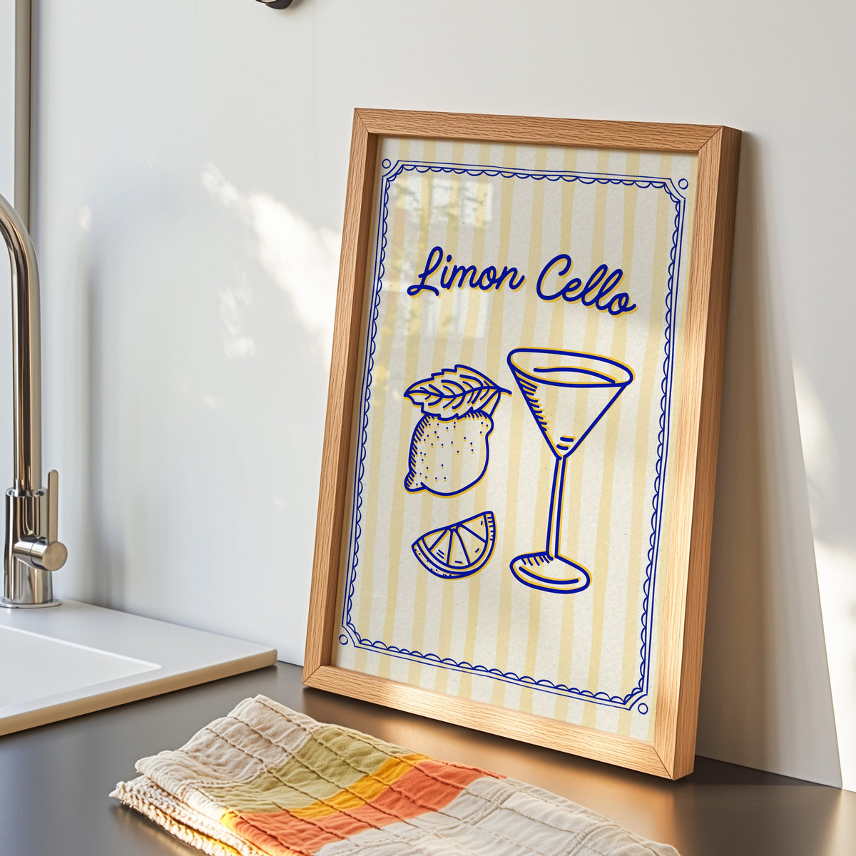 Limoncello martini print in an oak frame by the kitchen sink beside a striped tea towel