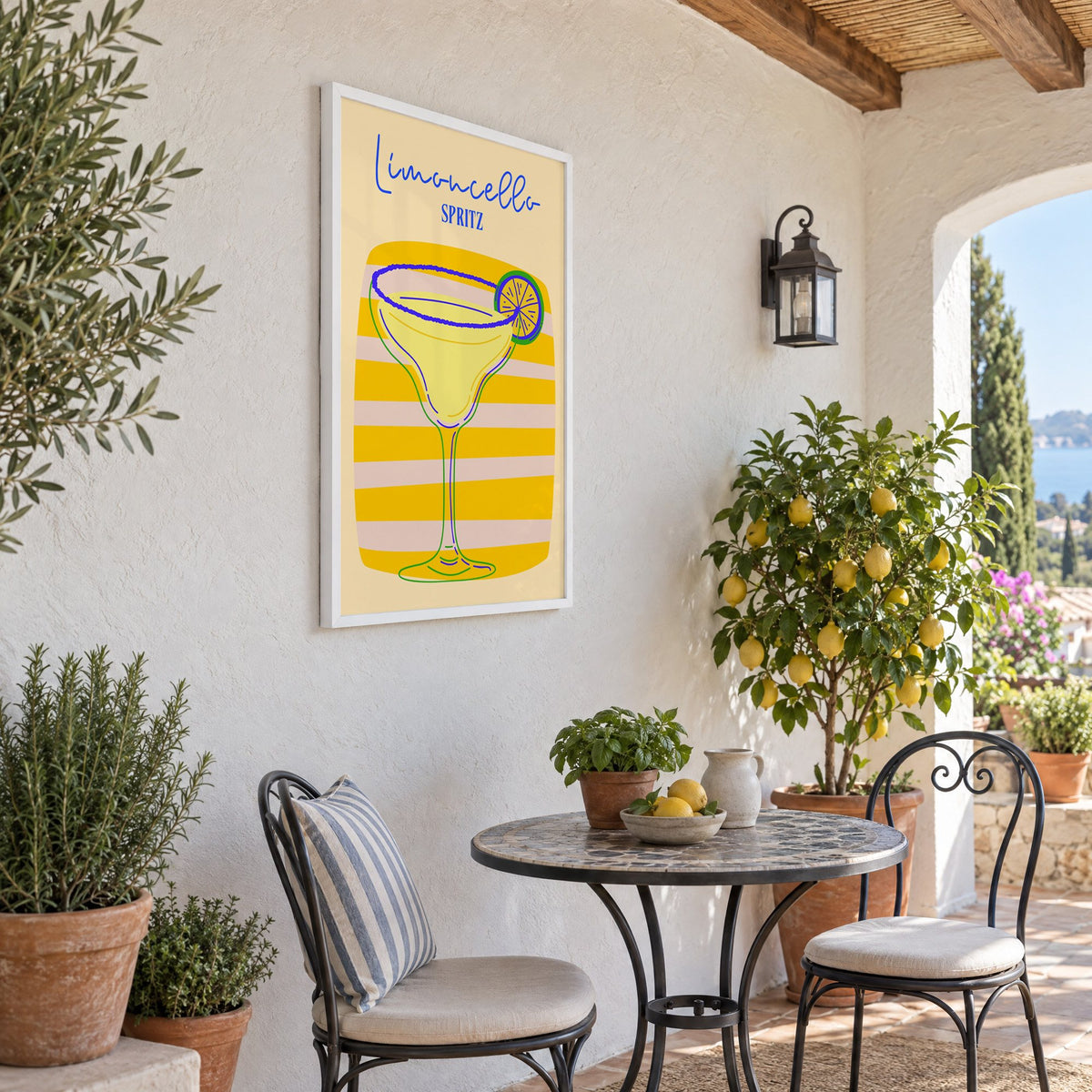 Limoncello Spritz yellow stripe print in a white frame on a sunny patio wall beside a potted lemon tree