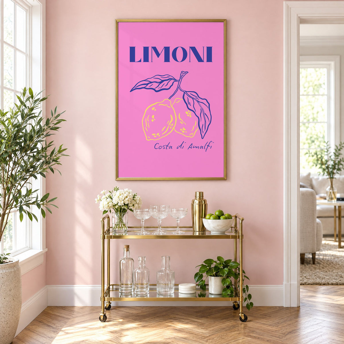 LIMONI Costa di Amalfi lemon branch print in a brass frame on a blush pink wall above a gold bar cart with glassware