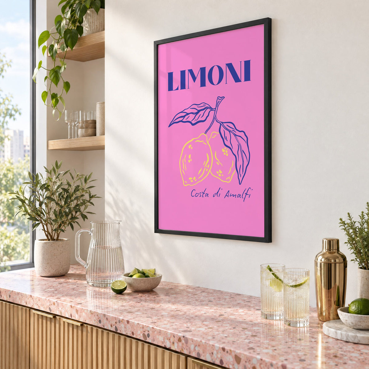 LIMONI Costa di Amalfi lemon branch print in a black frame above a pink terrazzo cocktail counter with limes, seen at an angle