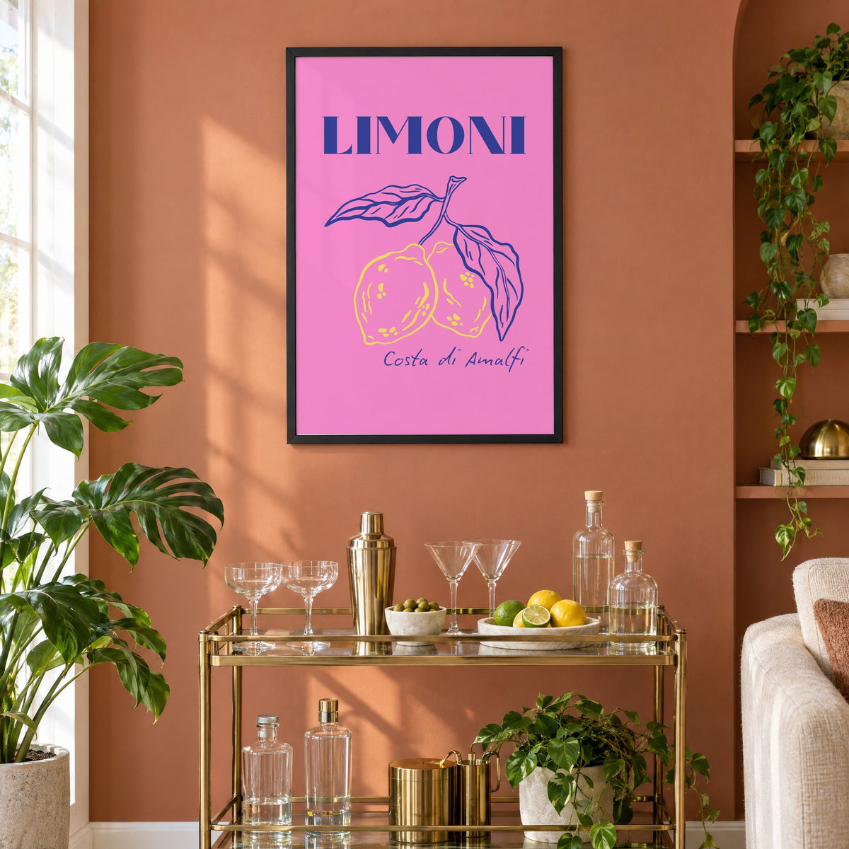 LIMONI Costa di Amalfi lemon branch print in a black frame on a terracotta wall above a brass bar cart with coupes and citrus