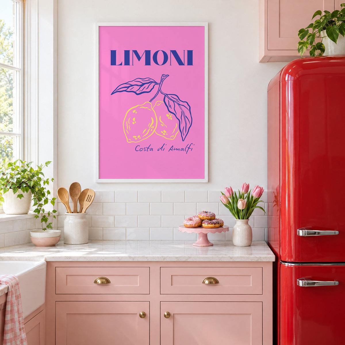 LIMONI Costa di Amalfi lemon branch print in a white frame above pink cabinets beside a red retro fridge