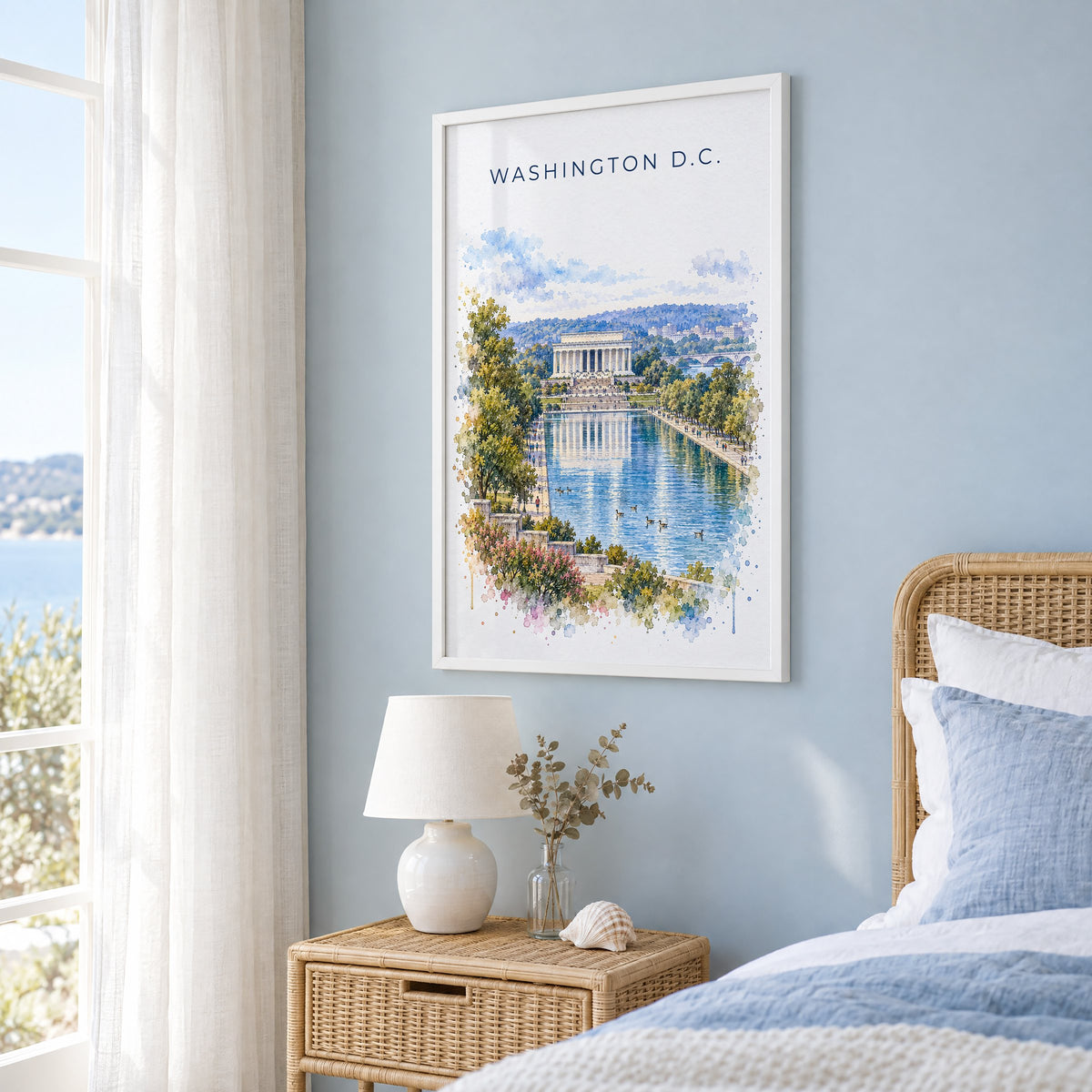 Lincoln Memorial watercolor print in a white frame on a pale blue wall beside a rattan bed in a coastal bedroom